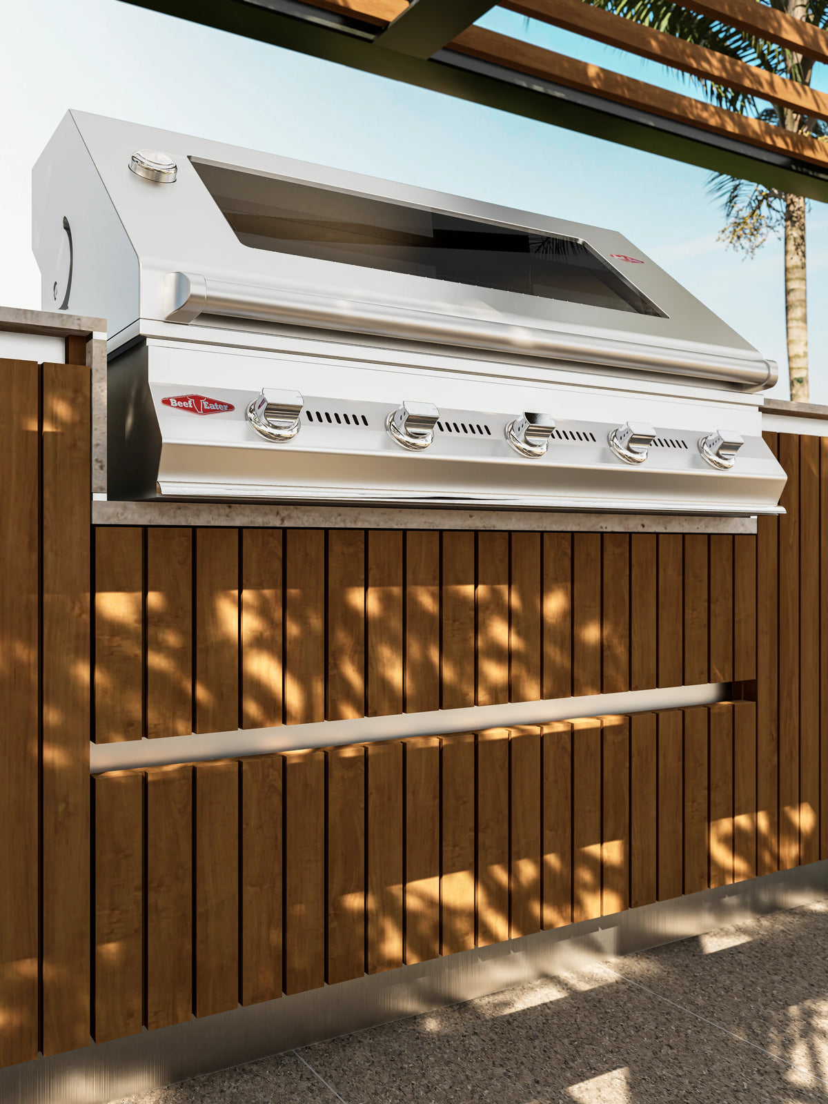Front view of the Al Fresco Kitchenette’s stainless steel grill above solid teak drawers and cabinetry with a travertine countertop.