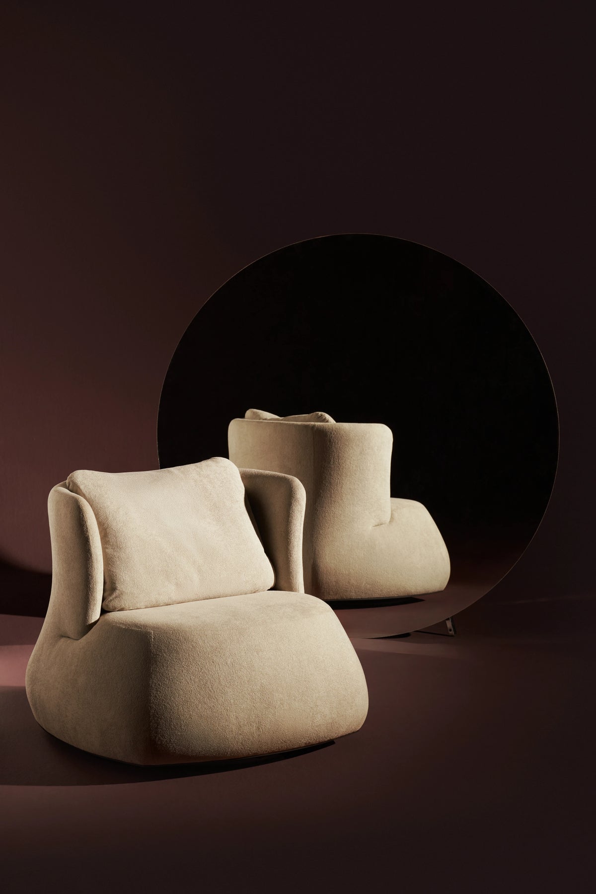 Cream Belly armchair with a duck feather-filled back cushion, wraparound U-shaped backrest, and grounded rounded base.