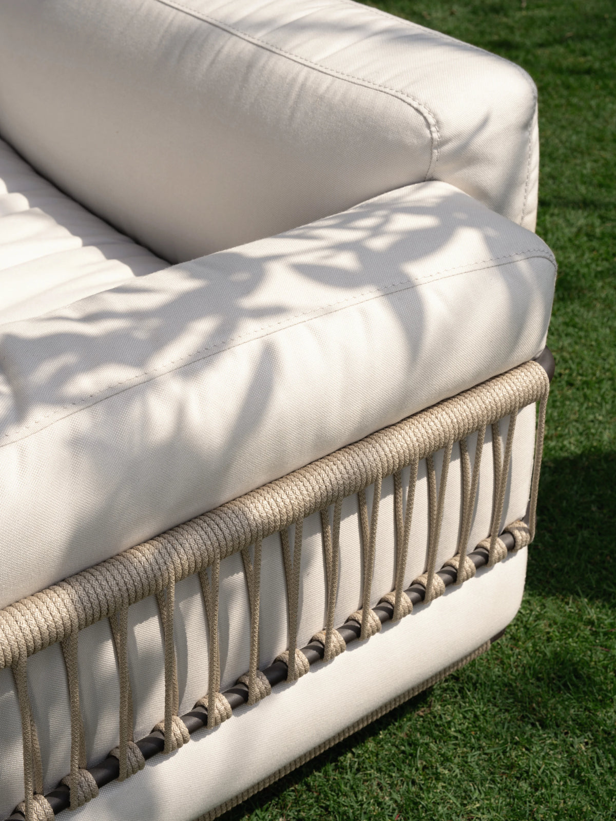 Close-up of the Bloom outdoor sofa’s cream cushions and handwoven beige rope detailing along the stainless steel frame.