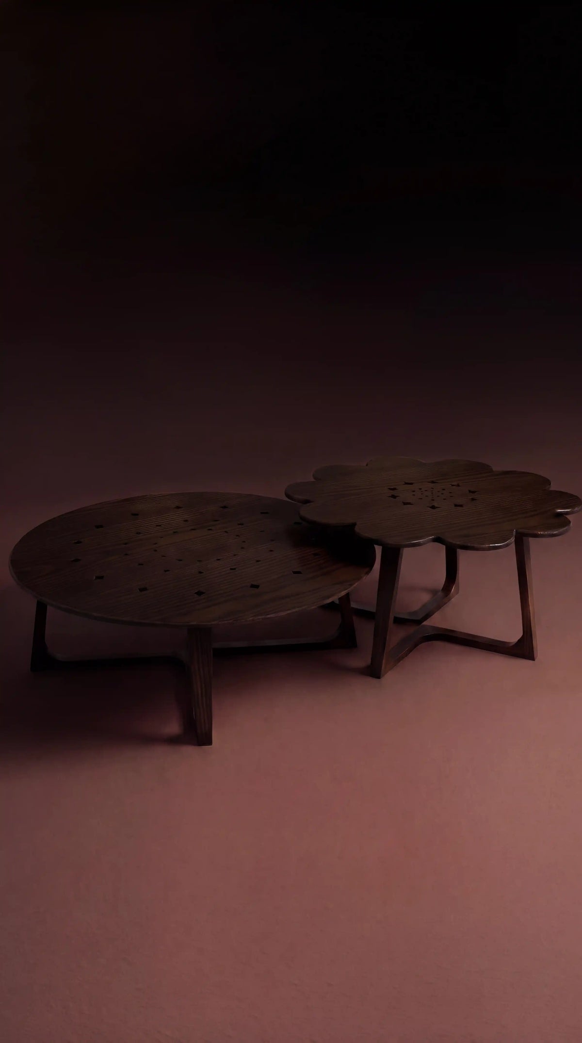 Two dark solid oak Blossom tables with circular and petal-shaped cutout tops, shown at different heights.