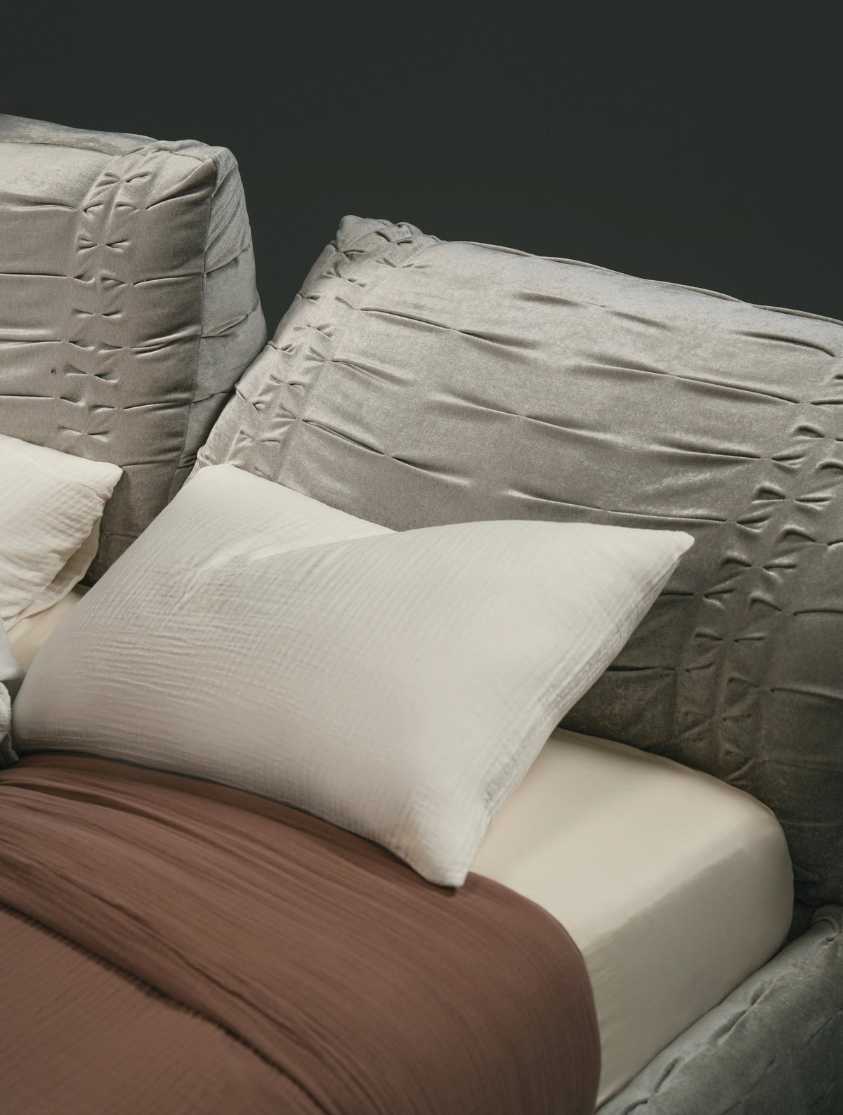 Close view of the Crusty bed’s flexible backrest sides and hand-stitched pleating, with one side shaped into a relaxed angle.