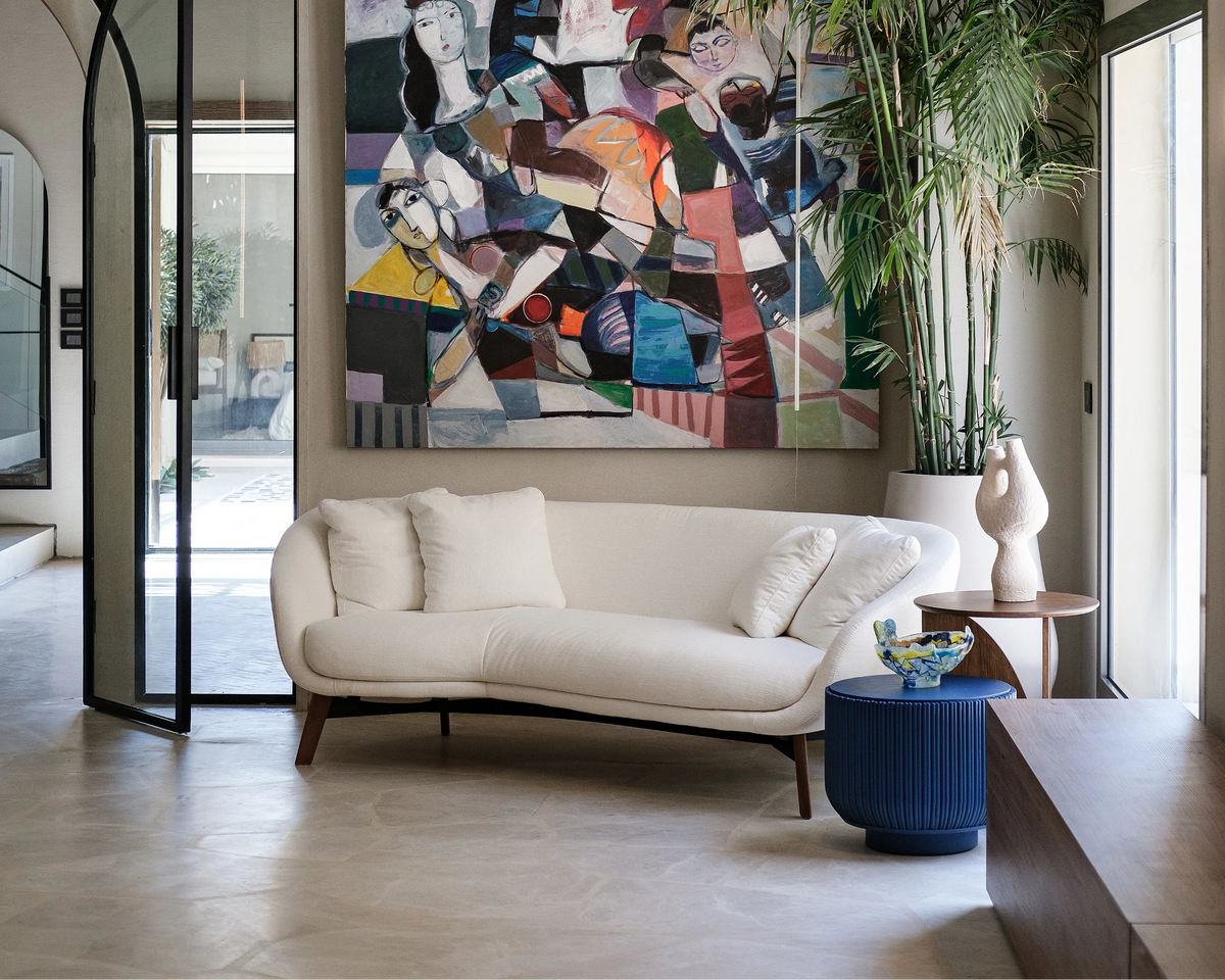 Beige Darby sofa with solid wood legs in a contemporary villa, styled with feather-filled cushions, artwork, and indoor greenery.