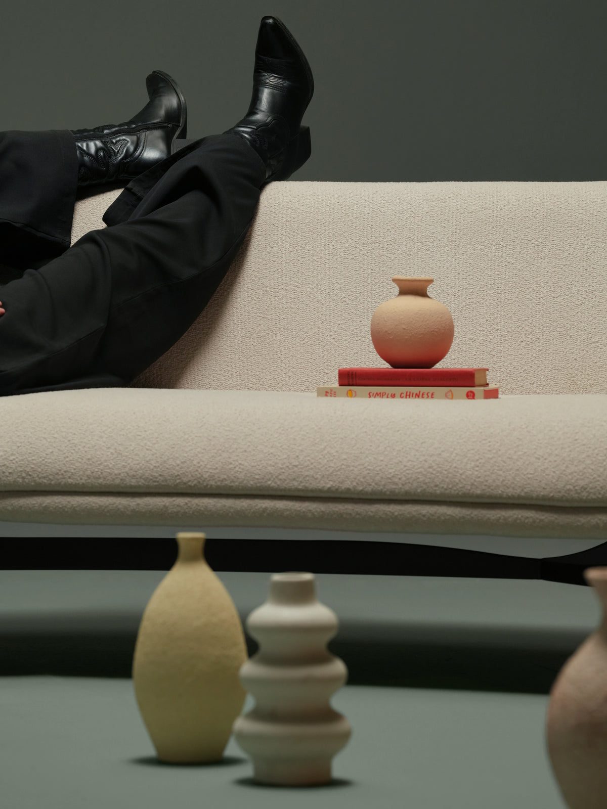 Close-up of the beige Darby sofa, showing its curved upholstered frame, cushioned seat, and angled solid wood legs.