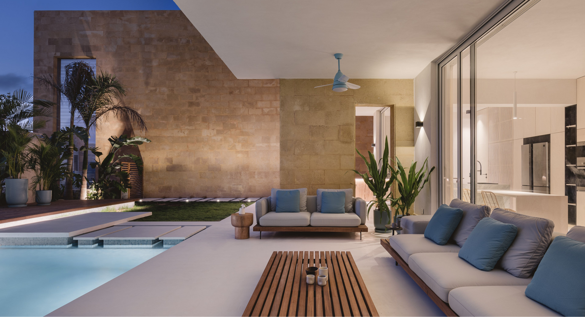 Dock outdoor sofa with grey and blue cushions arranged beside a slatted teak Dock table overlooking a swimming pool.