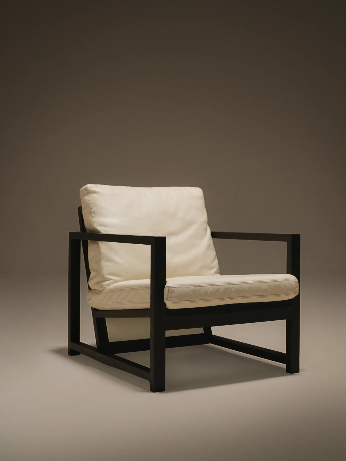 Front view of the beige Easy Slanted lounge chair with a reclined cushioned backrest and dark solid wood frame.