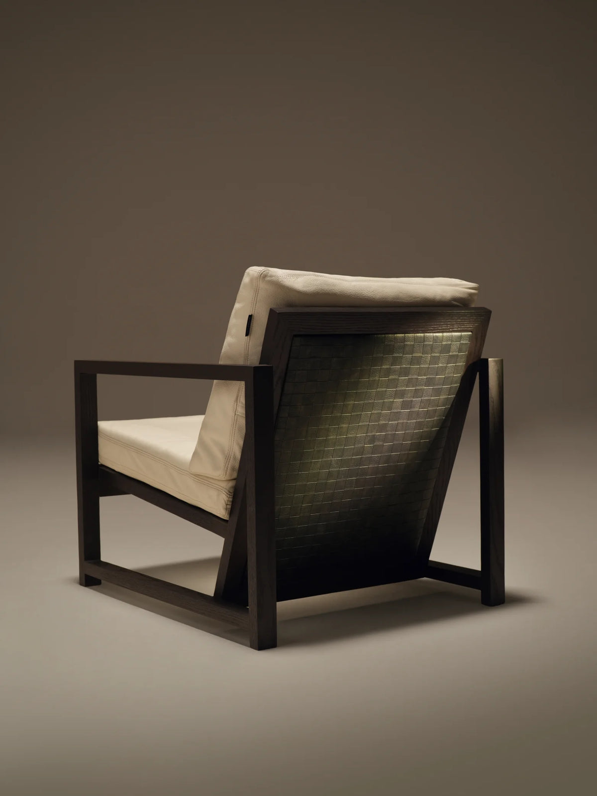 Rear view of the Easy Slanted chair showing its angled profile, dark solid wood frame, and contrasting woven leather back panel.