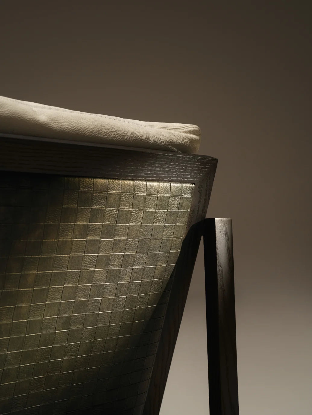 Close-up of the Easy Slanted chair showing its woven leather back panel, beige back cushion, and dark solid wood frame.