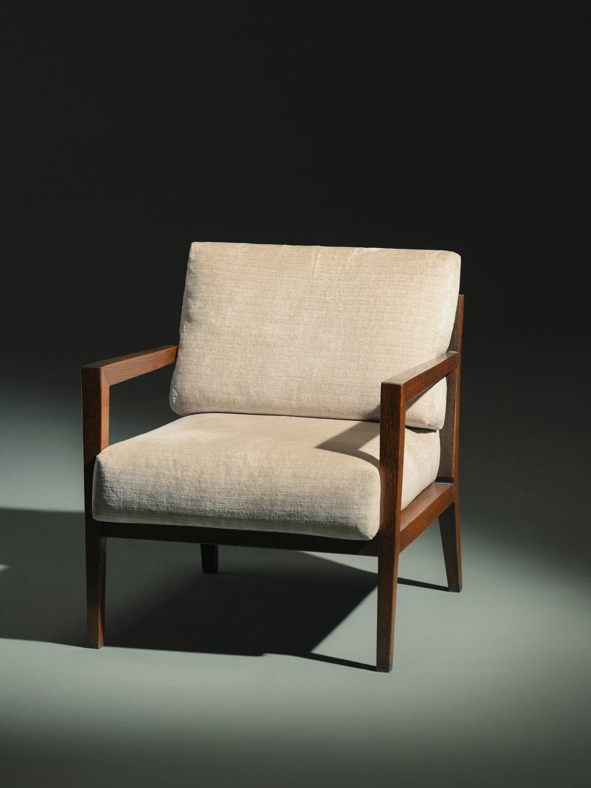 Front view of the beige Easy Upright lounge chair with polyurethane seat and back cushions supported by a dark solid wood frame.