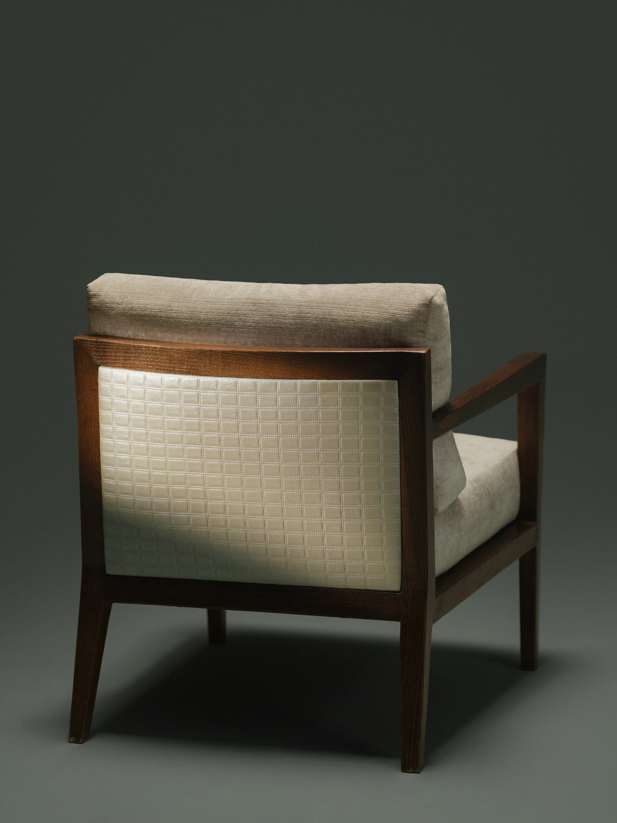 Rear view of the Easy Upright chair showing its beige cushions, dark solid wood frame, and contrasting patterned upholstered back panel.