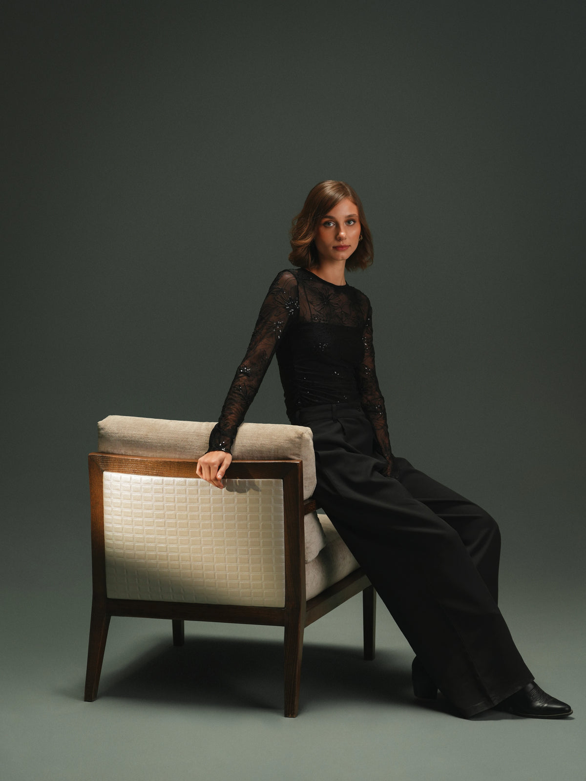 Woman seated on the Easy Upright chair, shown from behind with its contrasting patterned back panel and dark solid wood frame.