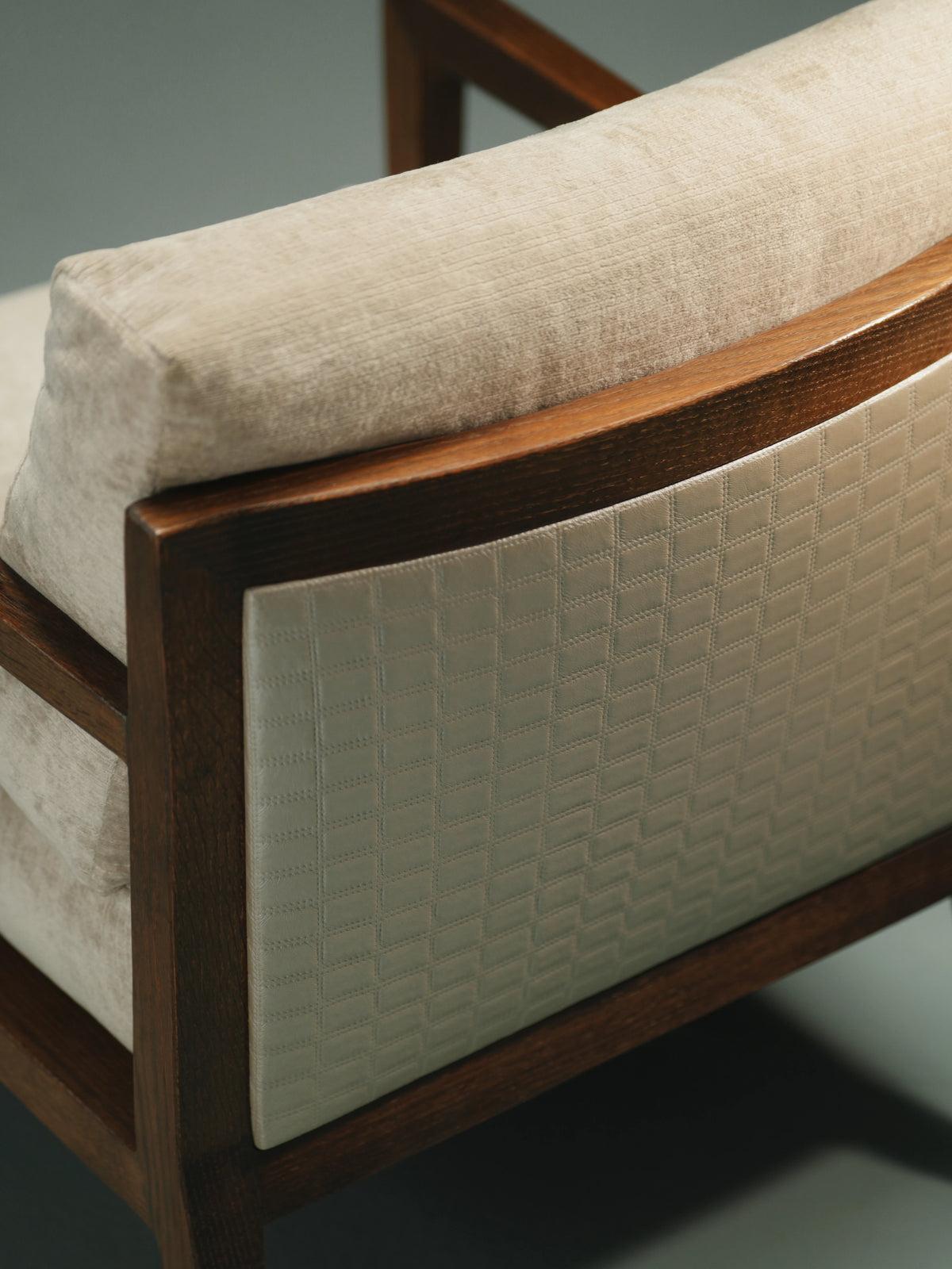 Close-up of the Easy Upright chair showing its beige back cushion, dark solid wood frame, and contrasting patterned upholstered back panel.