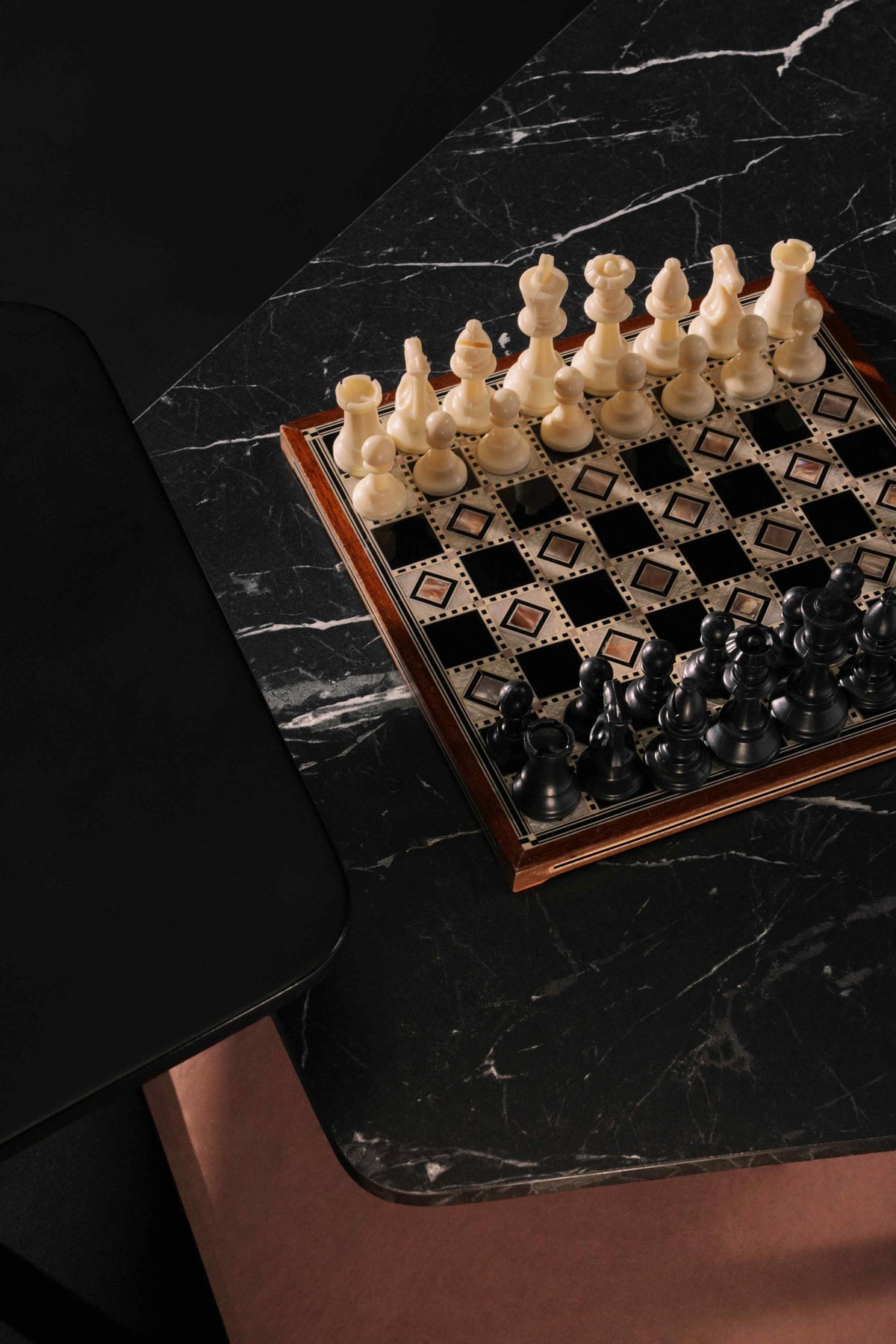 Close-up of the Echo table’s angular black marble laminate top, shown beside a contrasting black painted table.