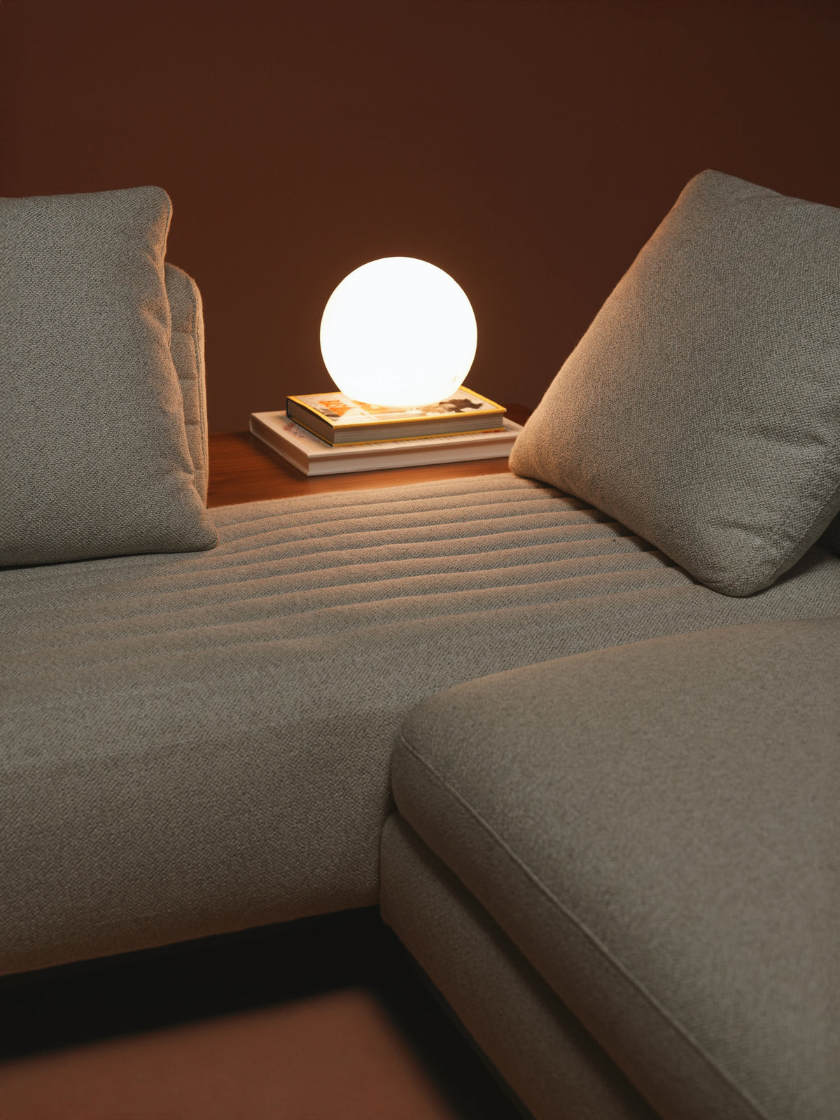 Close-up of the beige Edge modular sofa with feather back cushions, inverted seam stitching, and an integrated wooden table.
