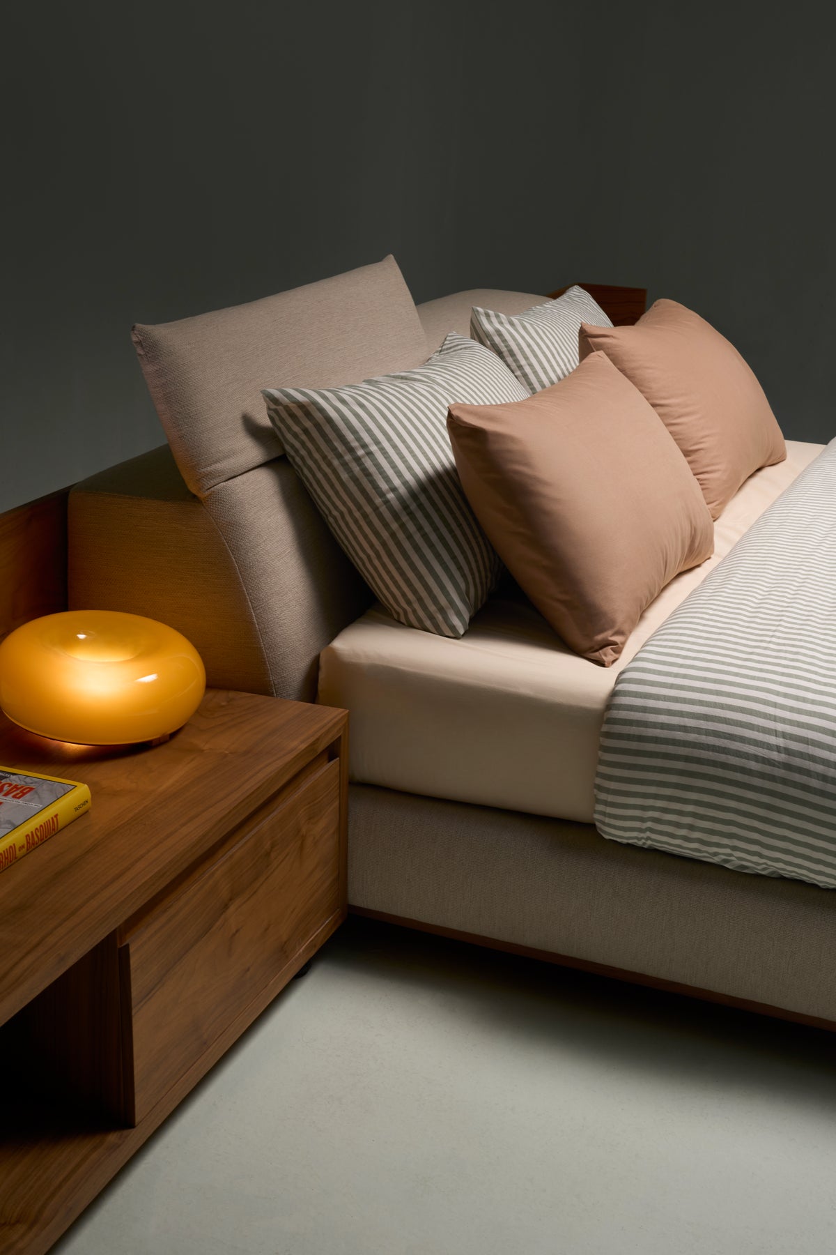 Close-up of Estrella Bed’s matching wood veneer commode beside platform mattress and slim upholstered headrest.