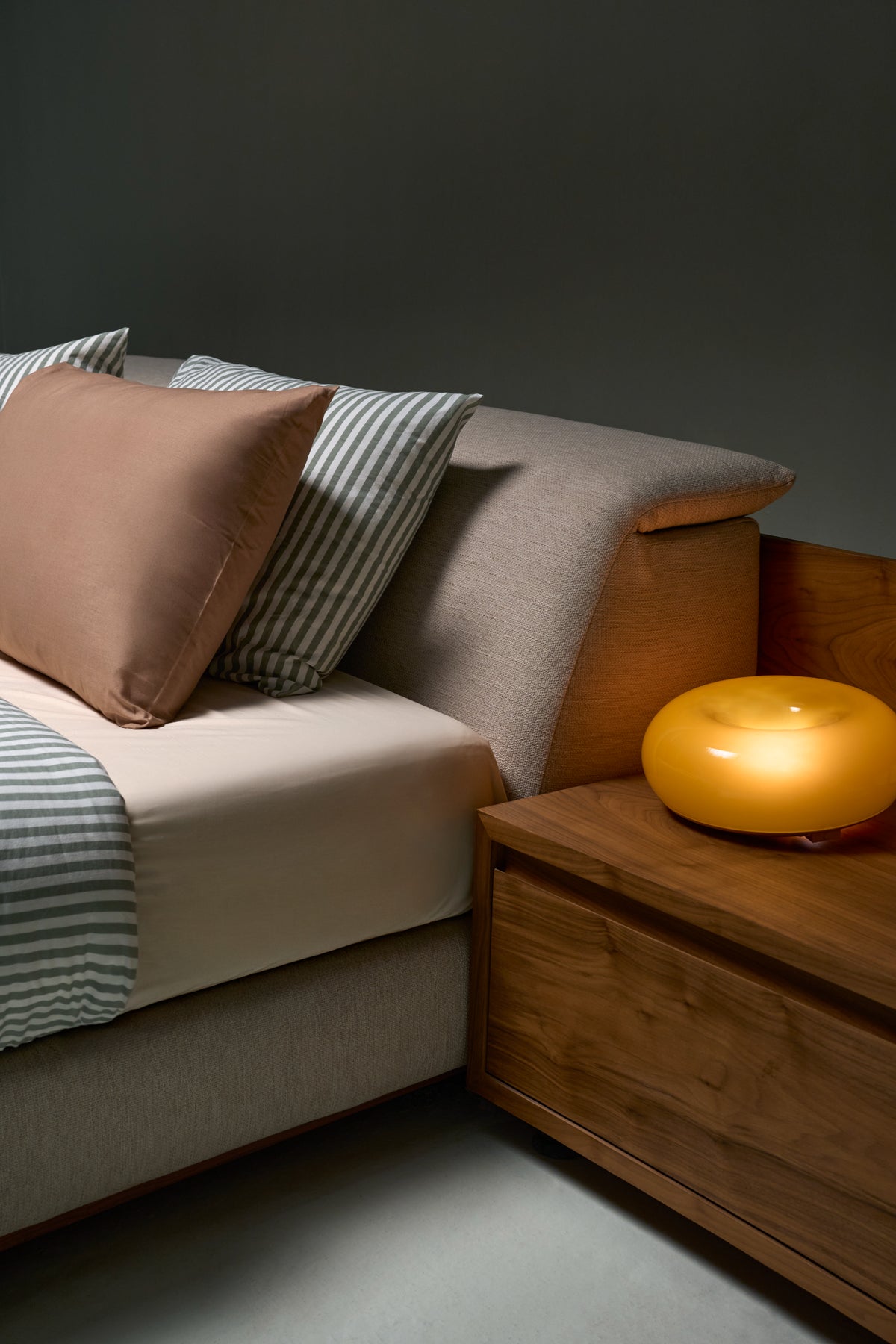 Close-up of Estrella Bed showing slim adjustable headrest with friction-catch mechanism and matching wood veneer commode.