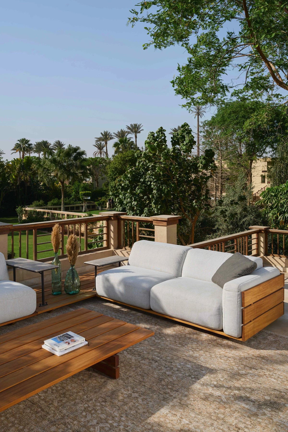 Grey Fatty outdoor sofa with contoured cushioning and solid teak frames, arranged around the matching teak Fatty table.