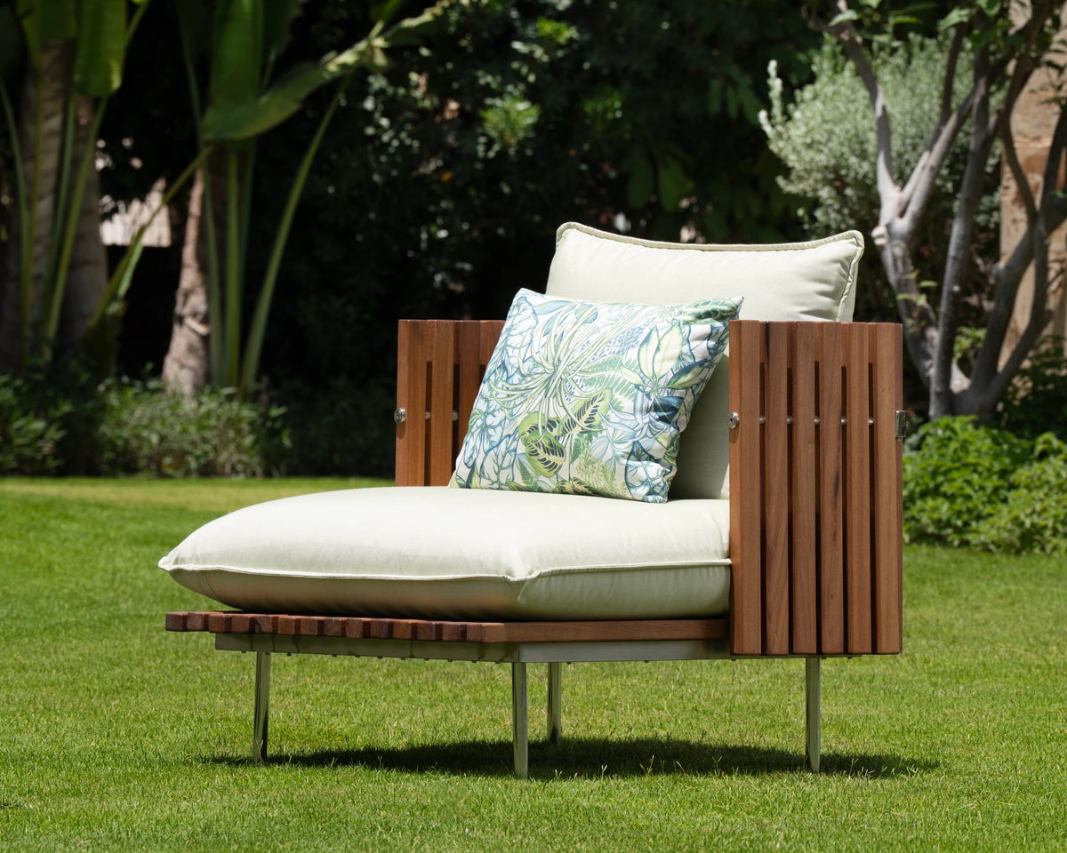 Fence armchair with teak wood slatted sides, cream upholstered cushions, and stainless steel legs, styled outdoors on a garden lawn.