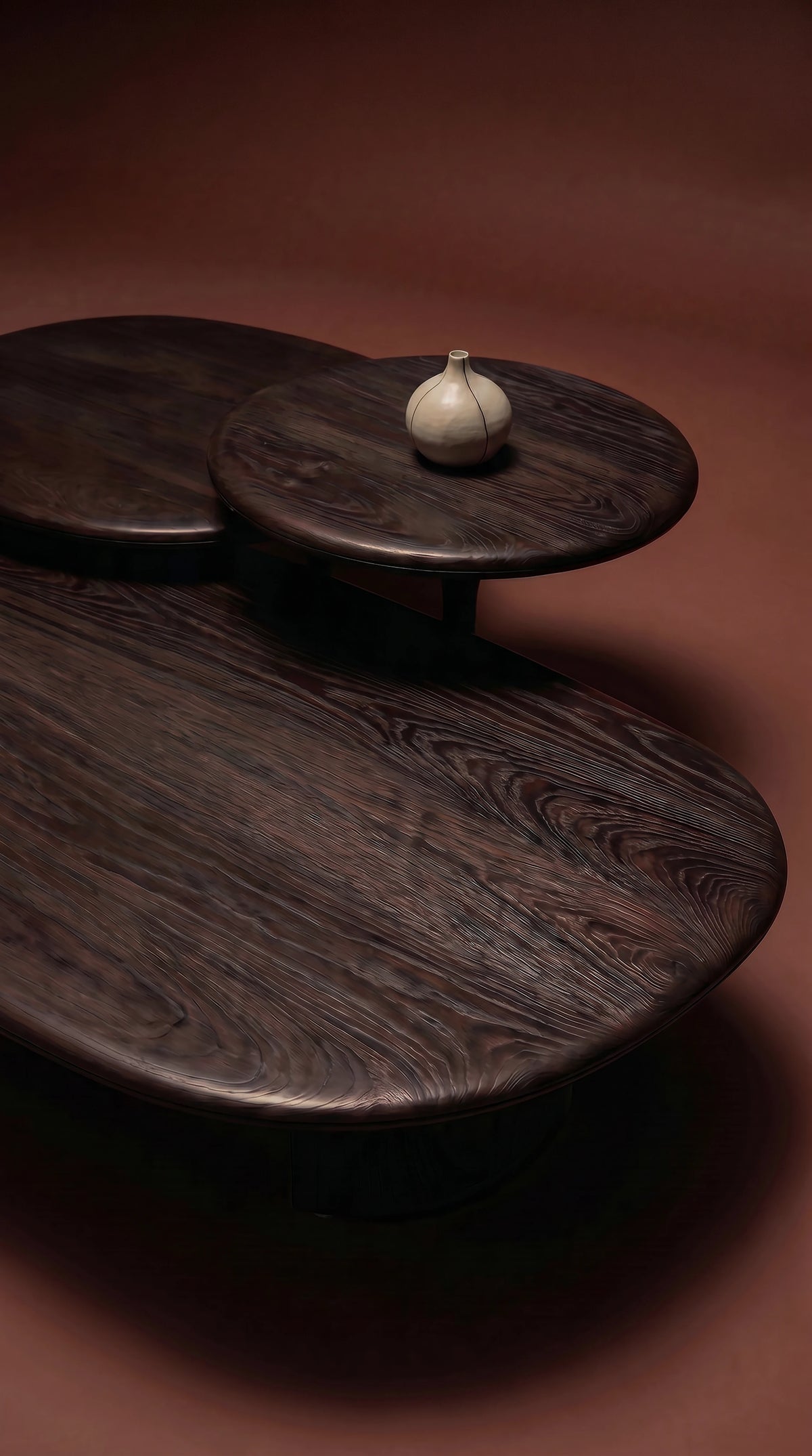 Close-up of the dark solid oak Glide coffee table set, showing the natural grain, rounded surfaces, tapered edges, and carved tabletop splits.