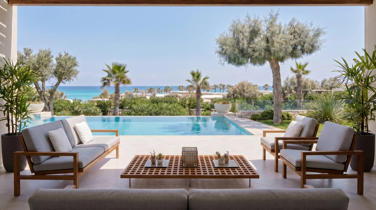 Hive outdoor furniture set with a solid teak sofa, two matching armchairs and a lattice coffee table overlooking a pool and the sea.