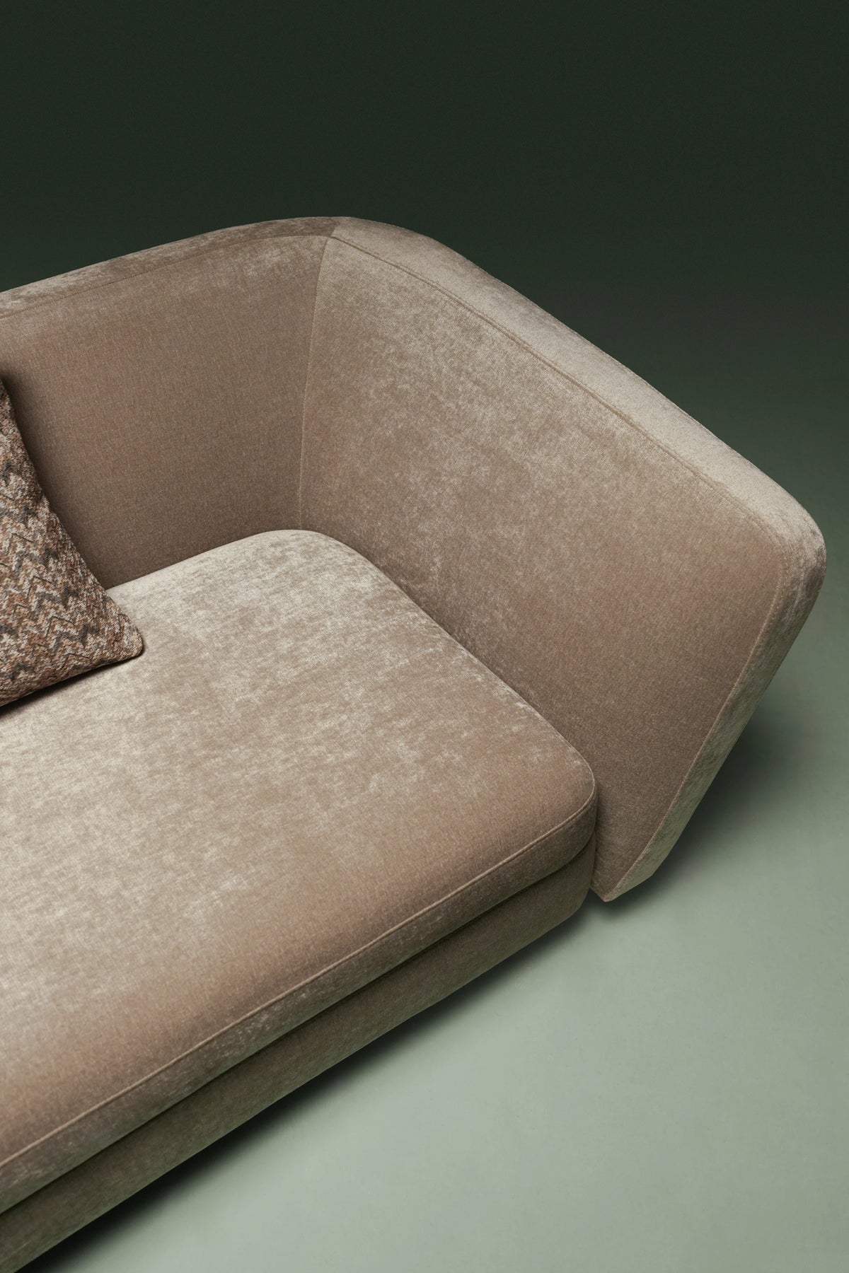 Close-up of the beige Kirby sofa, highlighting its asymmetrical curved backrest, rounded edge, and upholstered seat cushion.