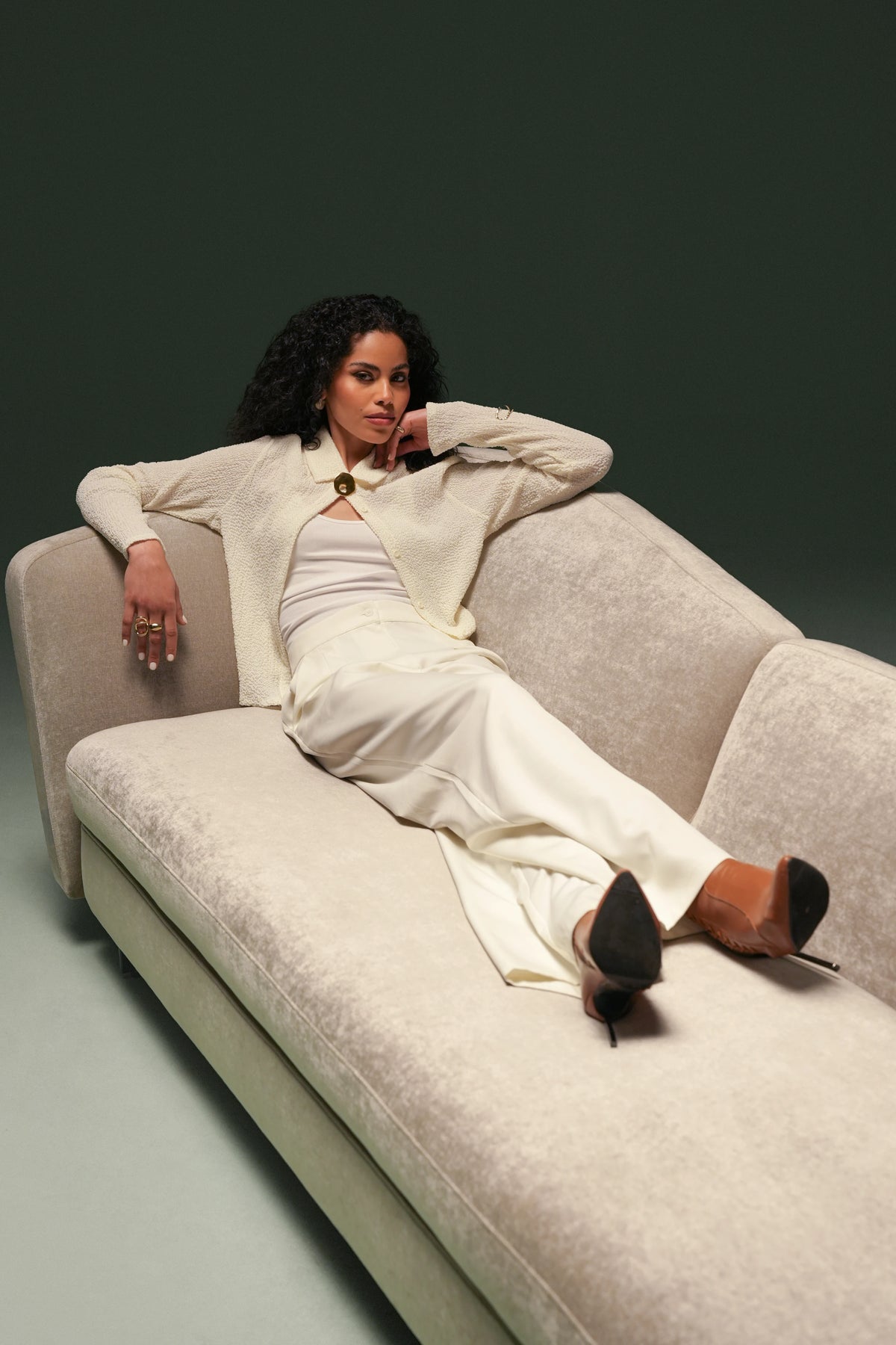 Woman reclining across the elongated Kirby sofa, showing its spacious seat and curved backrest with contrasting heights.