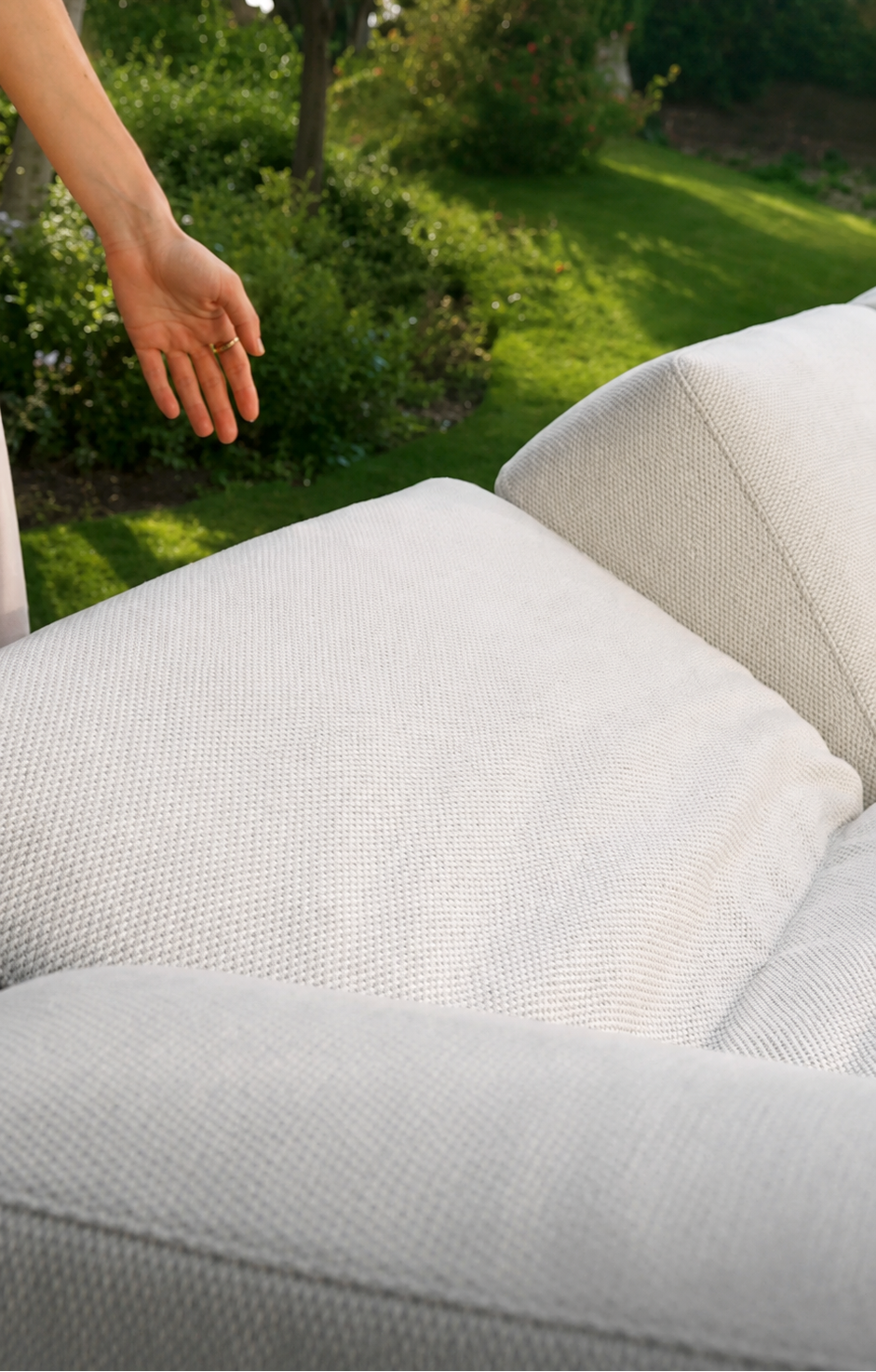 Close-up of the Lodge outdoor sofa’s white textured seat and back cushions in a garden setting.