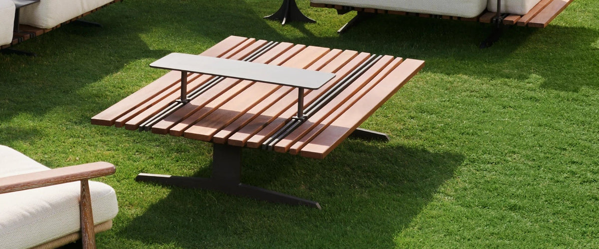 Close view of the Lodge outdoor table with mixed-width teak slats, stainless steel inlays, and a raised rectangular accent table.