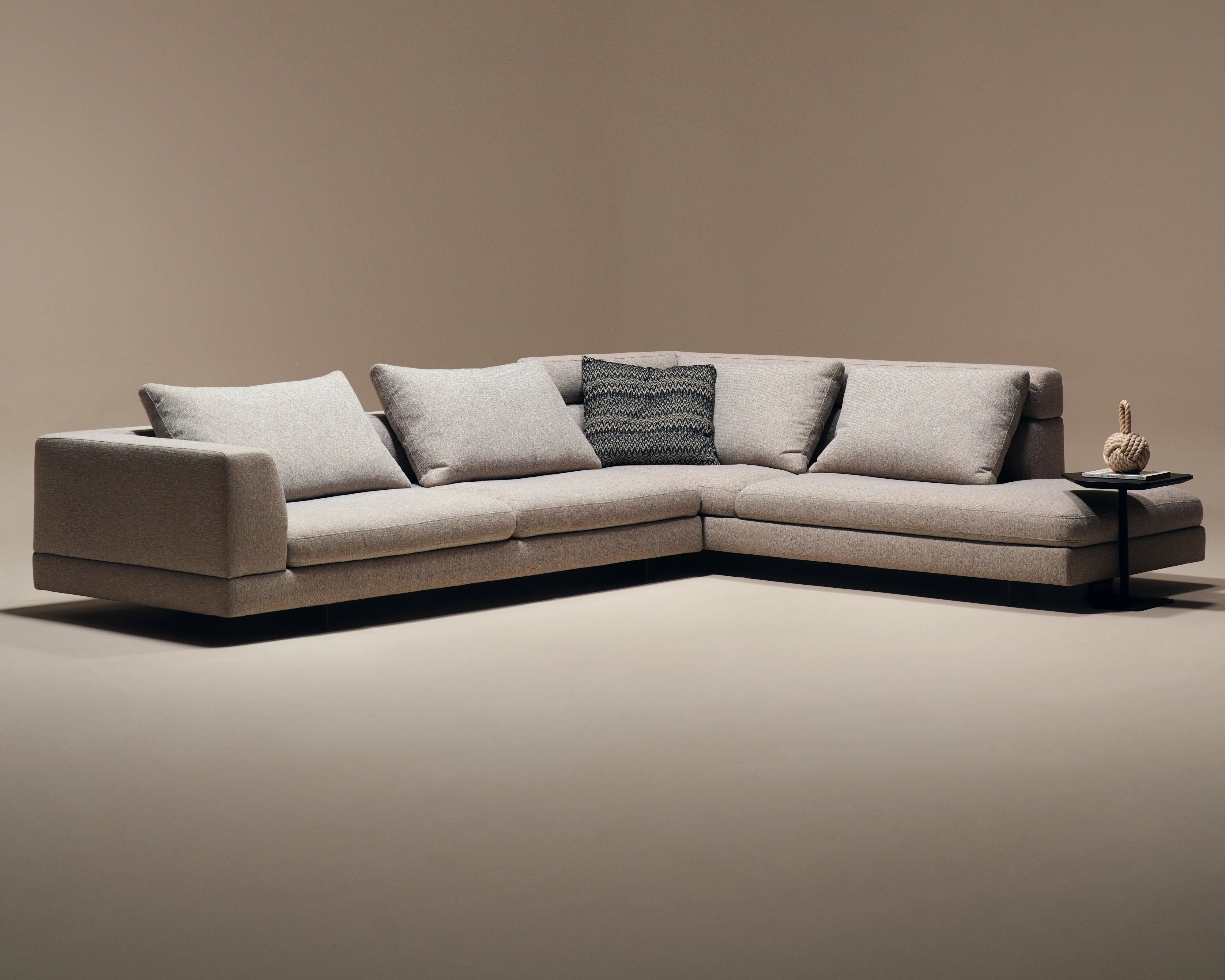 Beige Monti modular sectional sofa with a corner layout, deep seat cushions, feather-filled back cushions, and mixed back heights.