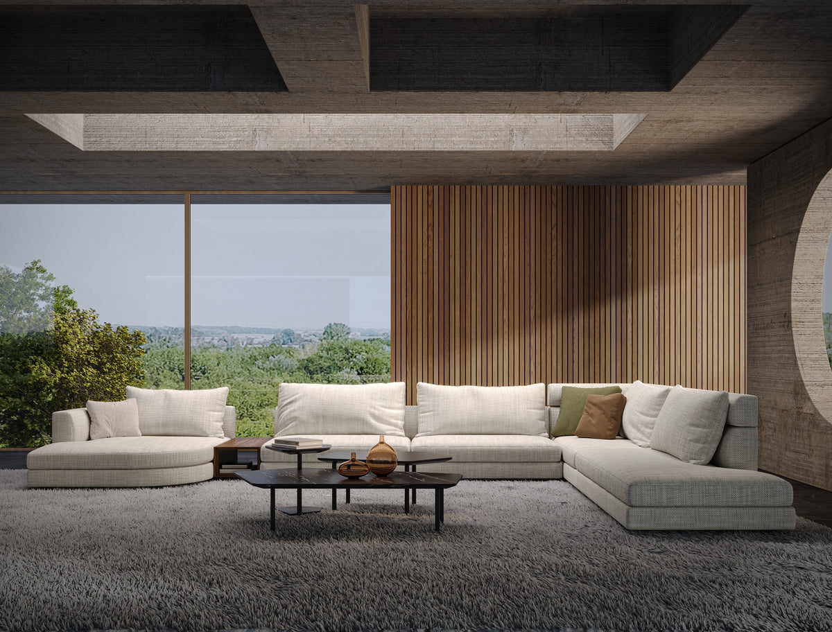 Beige Monti modular sectional sofa arranged with straight and curved seating modules in a contemporary living room overlooking the landscape.