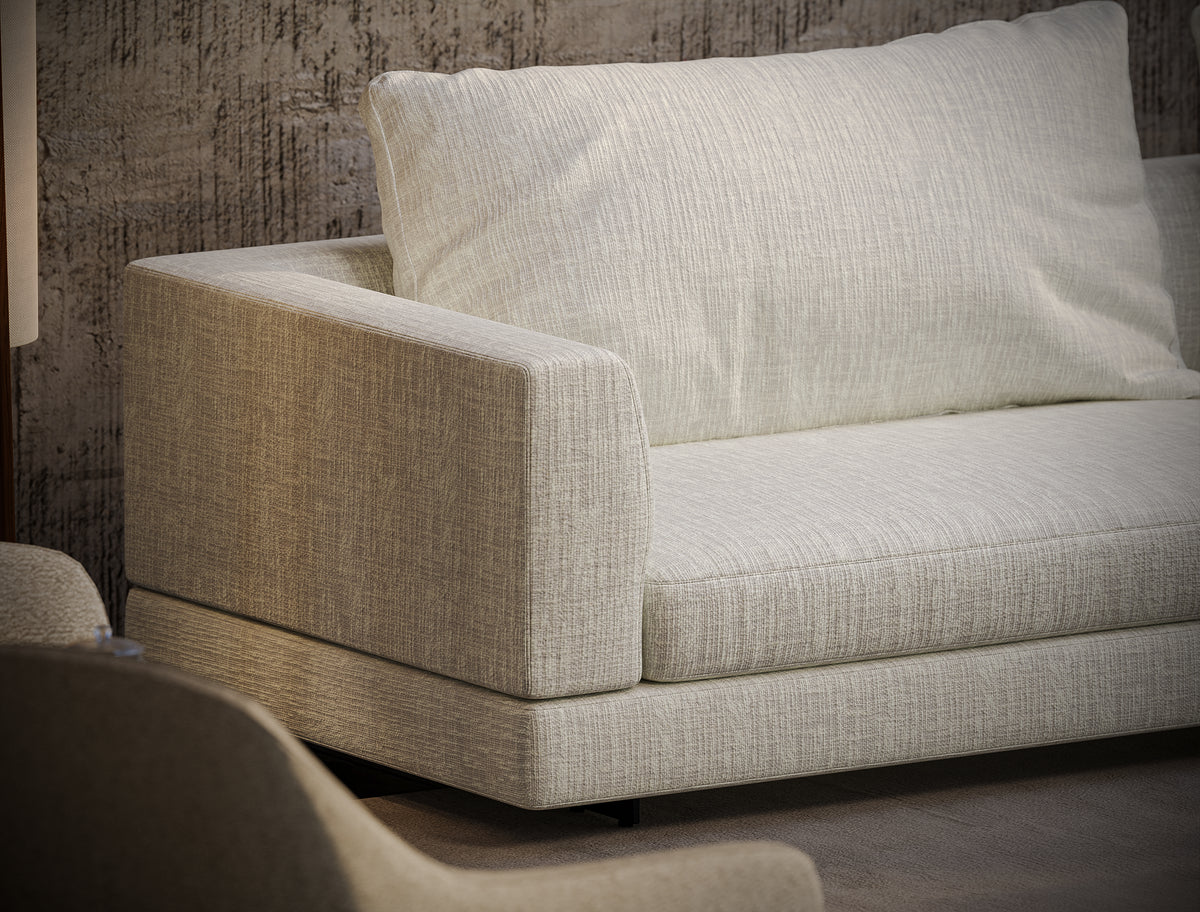 Close-up of the Monti sofa in textured beige upholstery, showing its tailored armrest, deep seat cushion, and feather-filled back cushion.