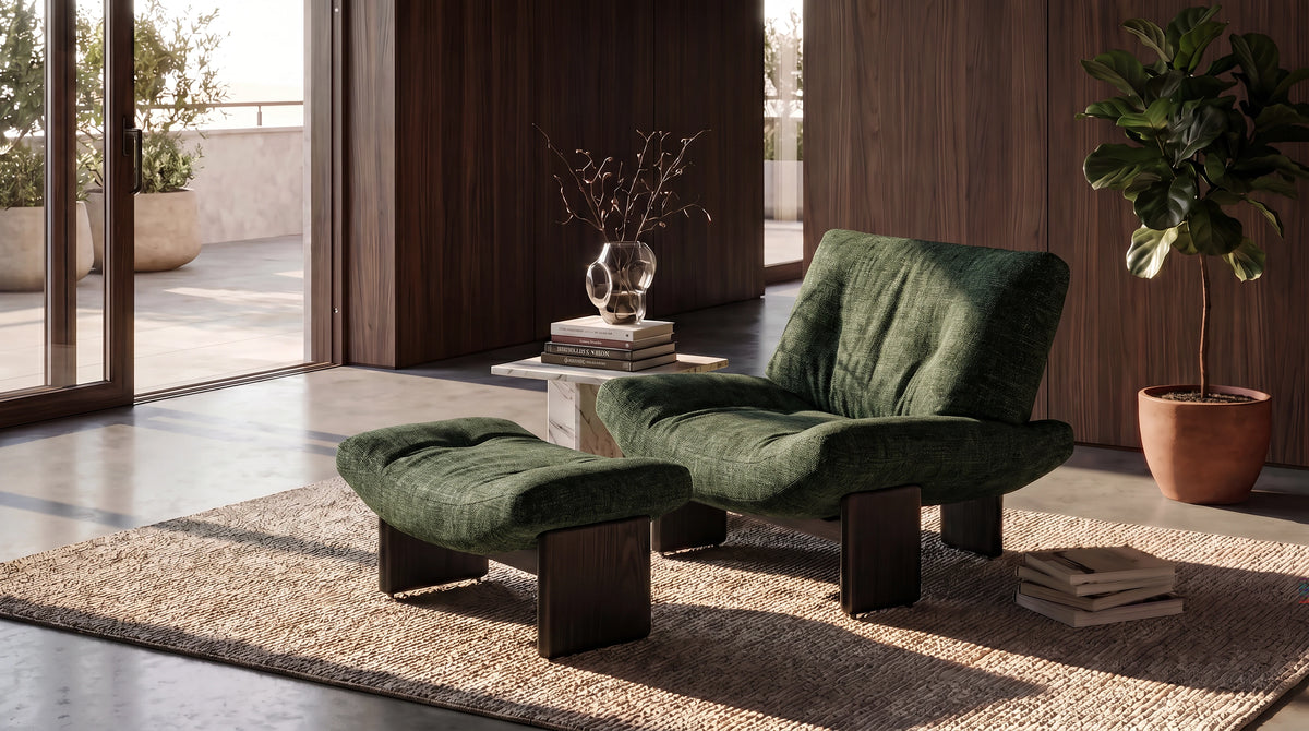 Green Muse lounge chair with matching footstool and dark solid wood slab legs in a living room with wood-paneled walls.