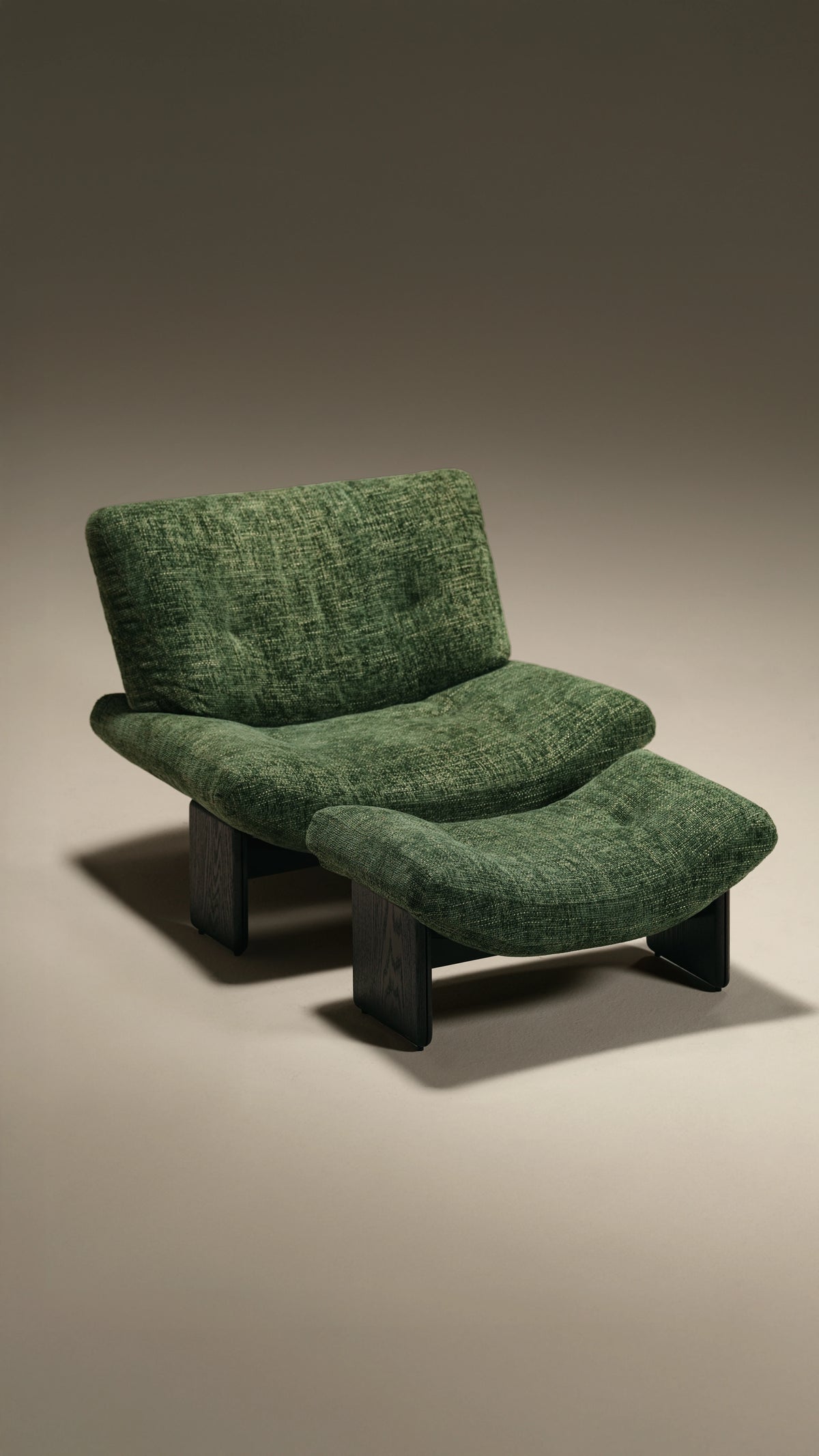 Angled view of the green Muse lounge chair and matching footstool, featuring light capitonné tufting and dark solid wood slab legs.