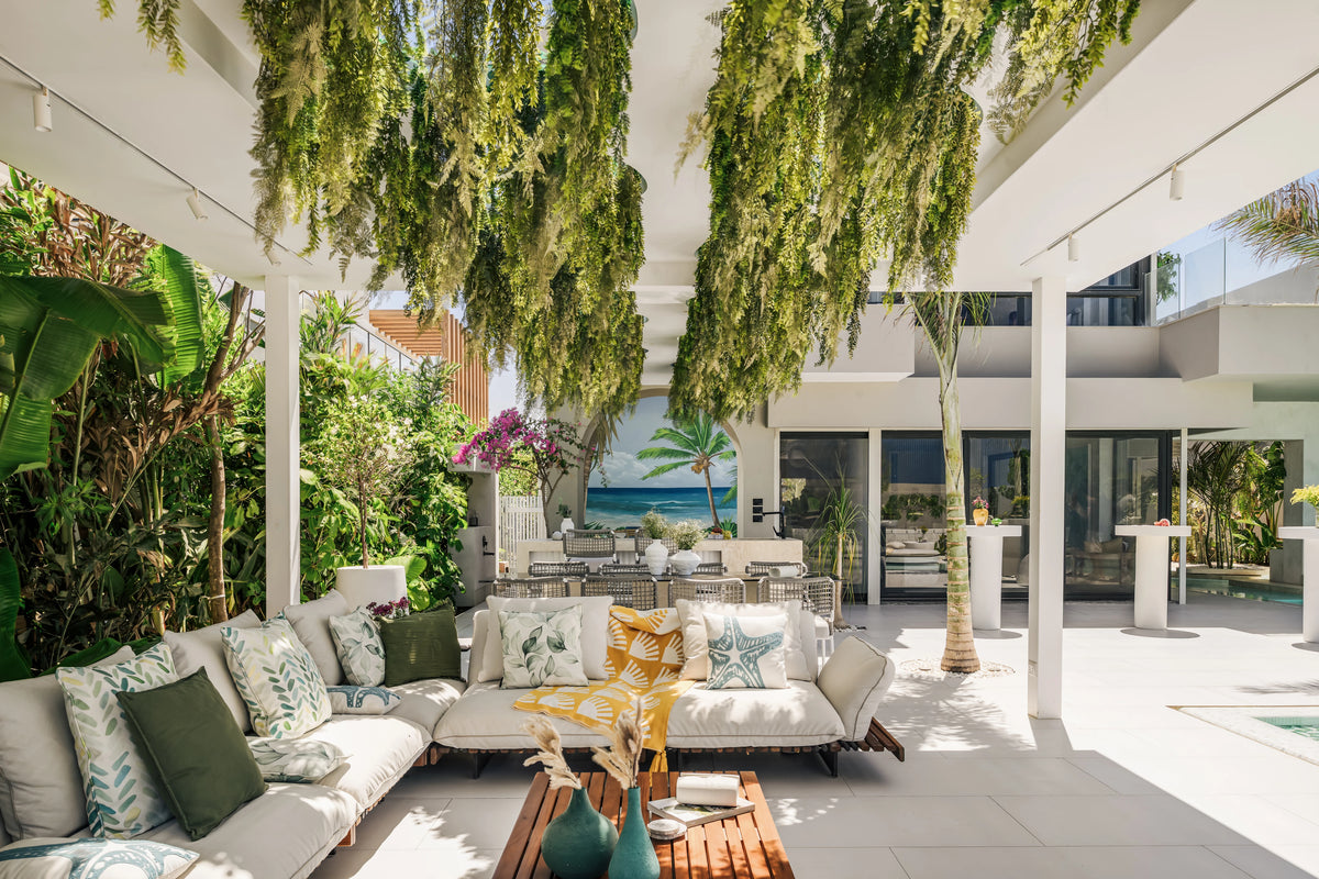 Nest outdoor sofa and chaise longue arranged around a slatted teak table on a patio beneath hanging greenery.