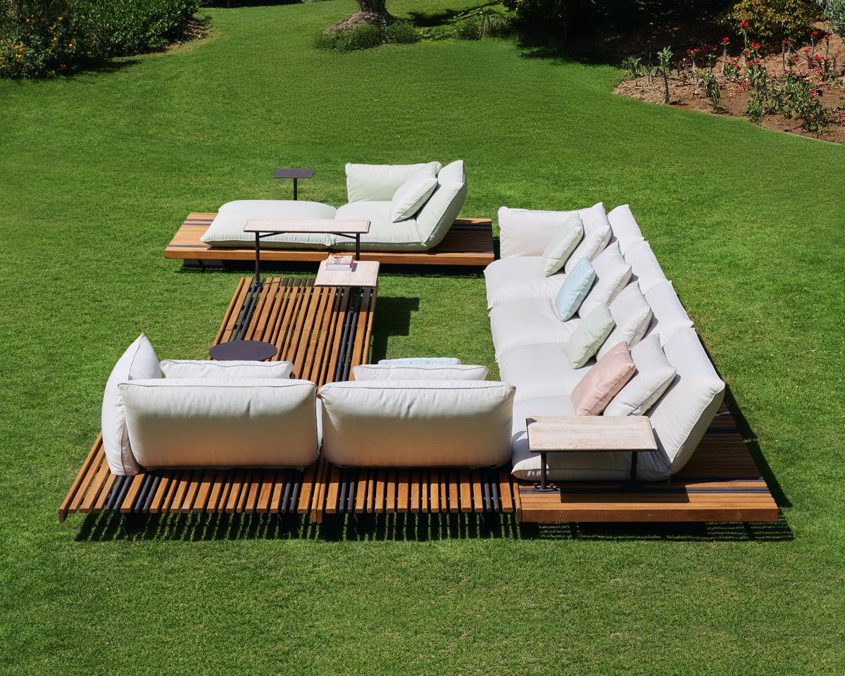 Overhead view of the white Nest outdoor sofa and chaise longue arranged around the slatted teak Nest table on a garden lawn.