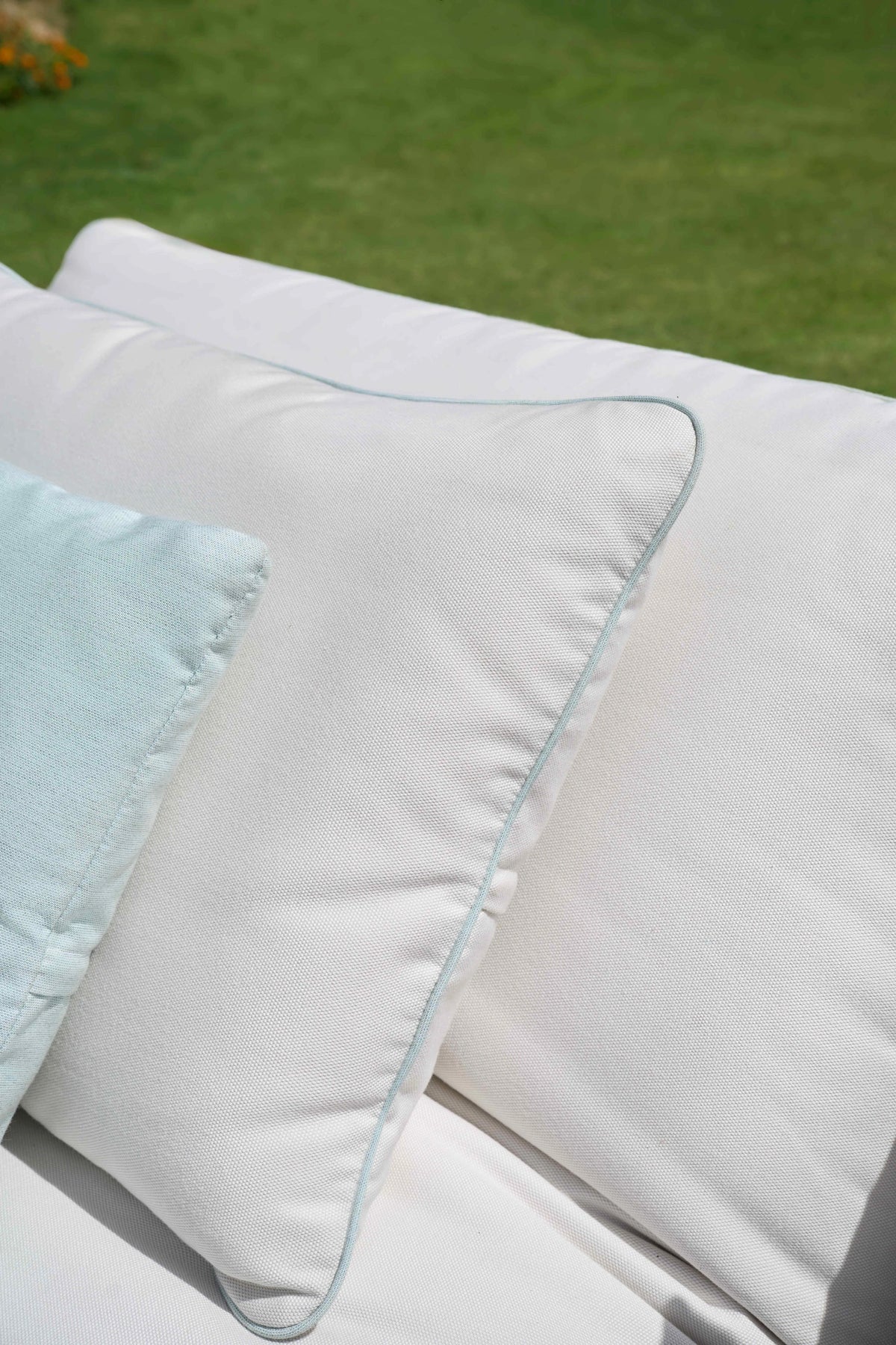 Close-up of the Nest outdoor sofa’s white cushions, highlighting the customizable piped seam detailing.