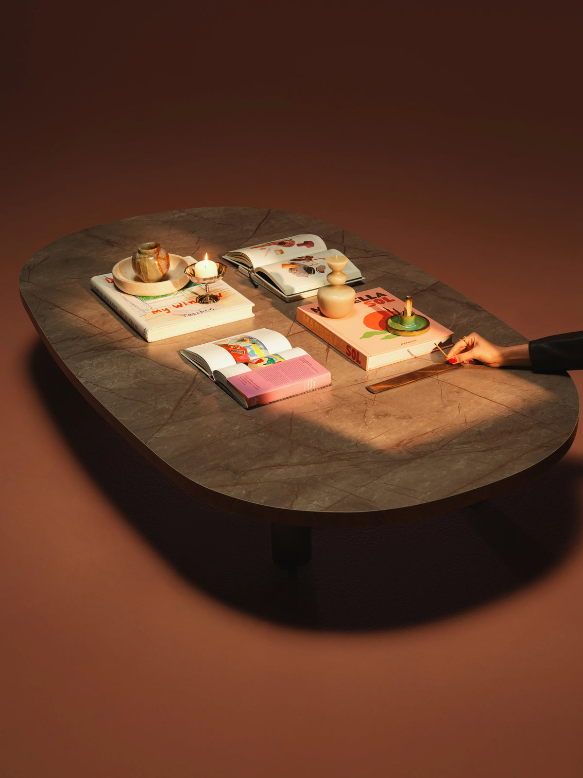 Overhead view of the Opal coffee table, showing its rounded marble laminate surface styled with books and decorative accessories.