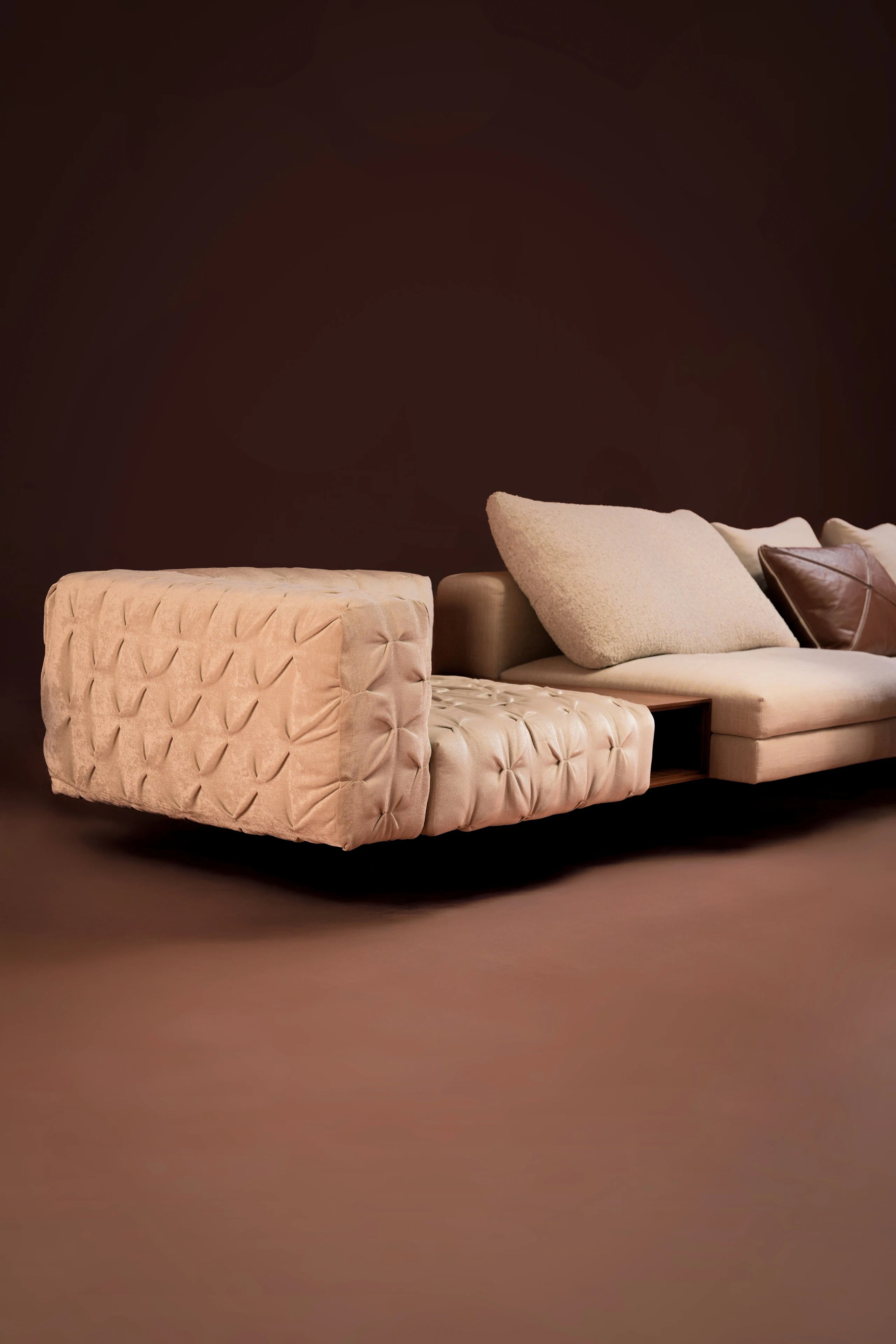 Close-up side view of the Paella Sofa highlighting its pinch pleating and frame in soft beige upholstery with duck feather cushions.