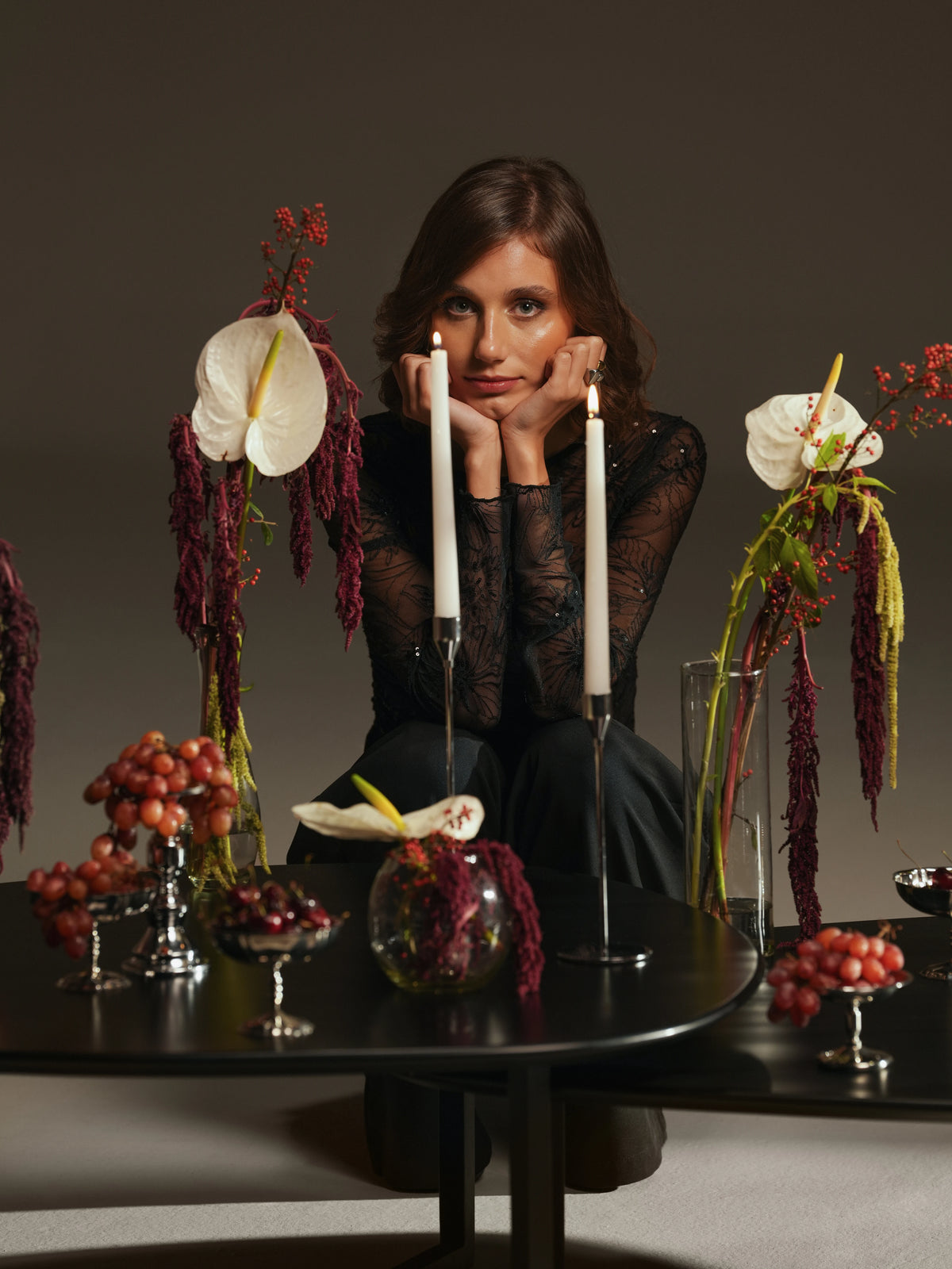Woman seated behind the black Pebble tables, showing their curved-edge tops, contrasting asymmetrical shapes, and varied heights.