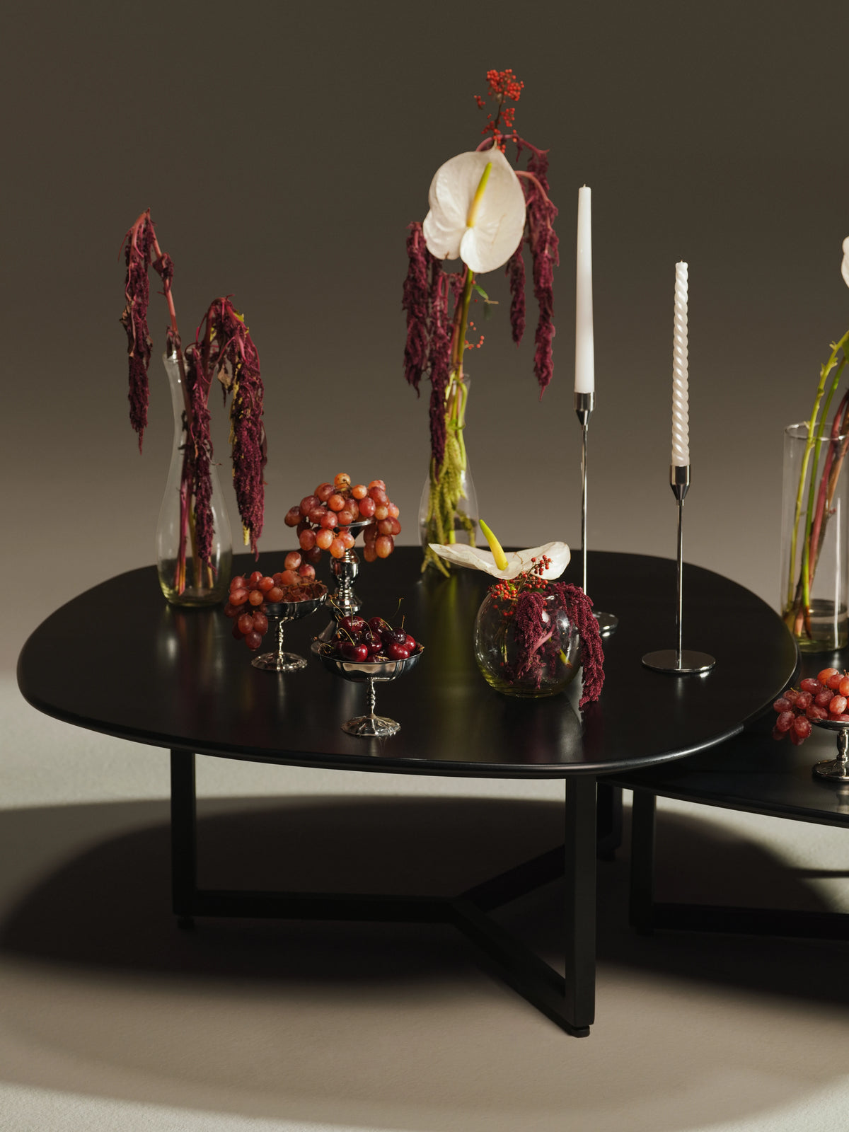 Detailed view of a black Pebble coffee table with a free-form painted plywood top, curved edge, and slim steel base.