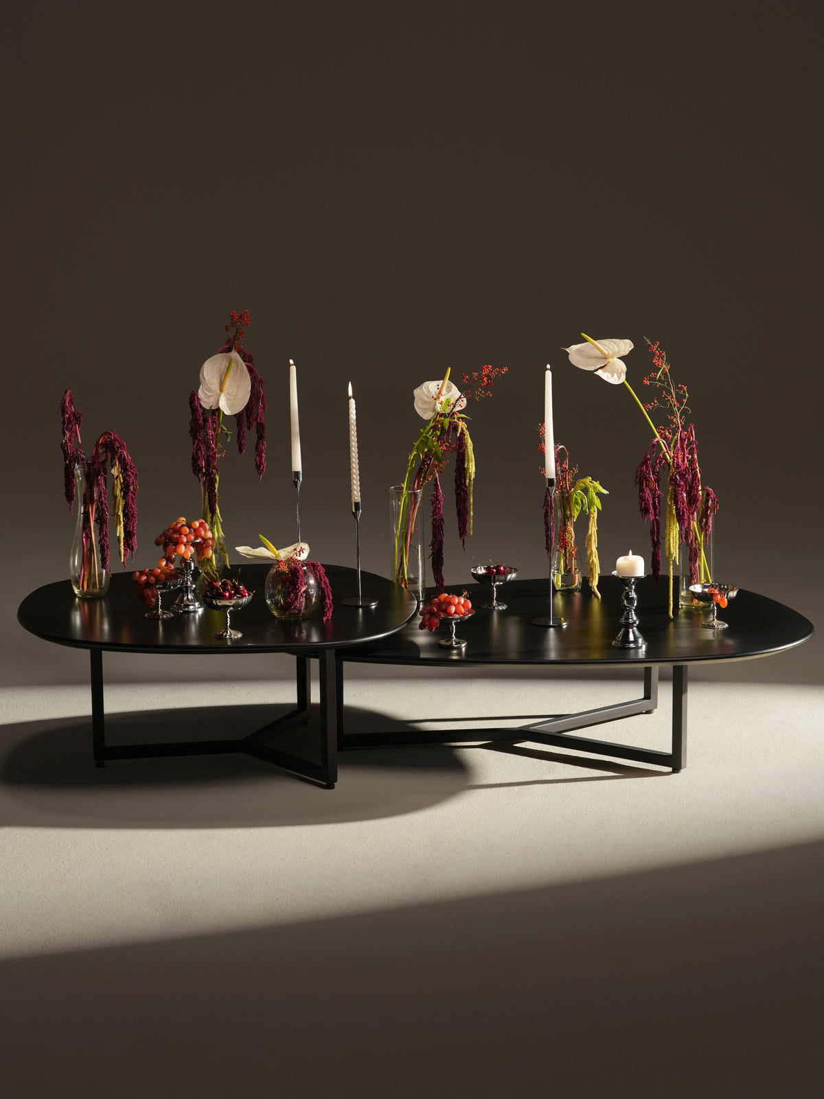 Full view of two black Pebble coffee tables paired together, with distinct free-form tops and slim electrostatic-coated steel legs.