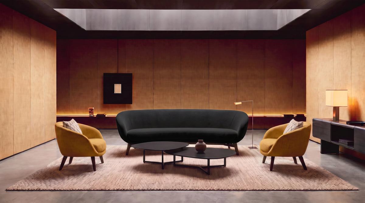 A modern living room setup featuring a curved black sofa as the central product, flanked by two mustard yellow armchairs on a textured beige rug, with two black nesting coffee tables in front. The room has warm wood-paneled walls and ceiling.