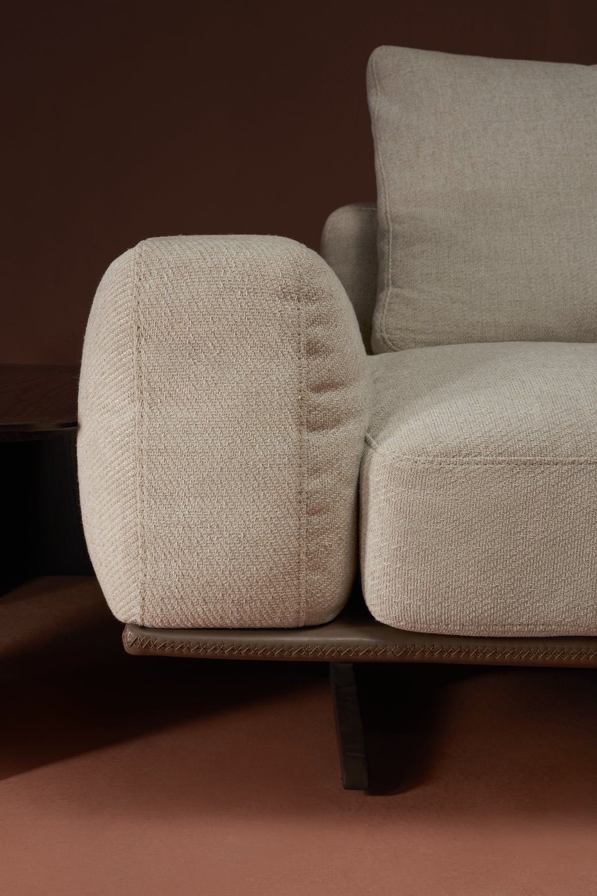 Close-up of Puff sofa arm and cushions, showing layered foam-and-feather filling and crisscross platform stitching detail.