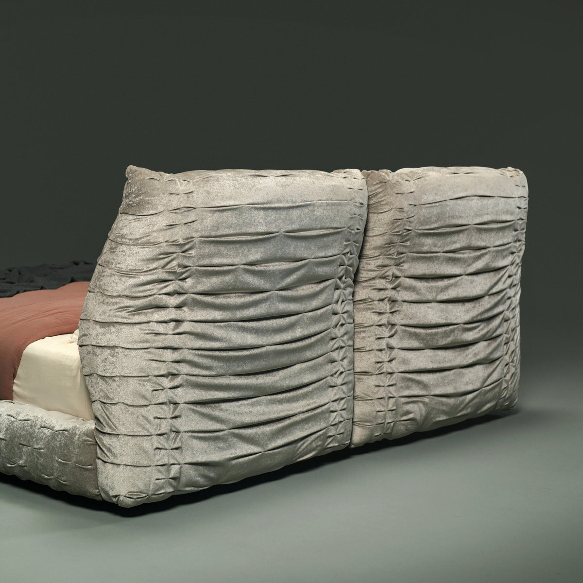 Rear view of the Crusty bed’s two upholstered backrests, highlighting the hand-stitched pleating across the grey fabric.