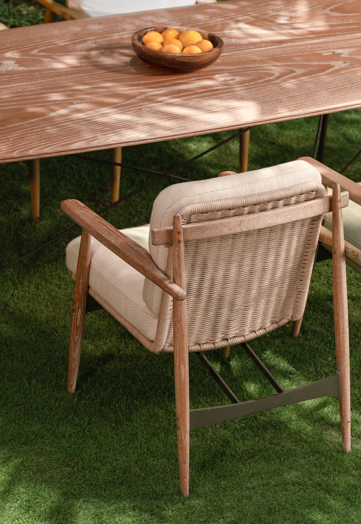 Close-up of Retro dining chair with woven backrest and cushioned seat in cream fabric, paired with Retro solid wood dining table.