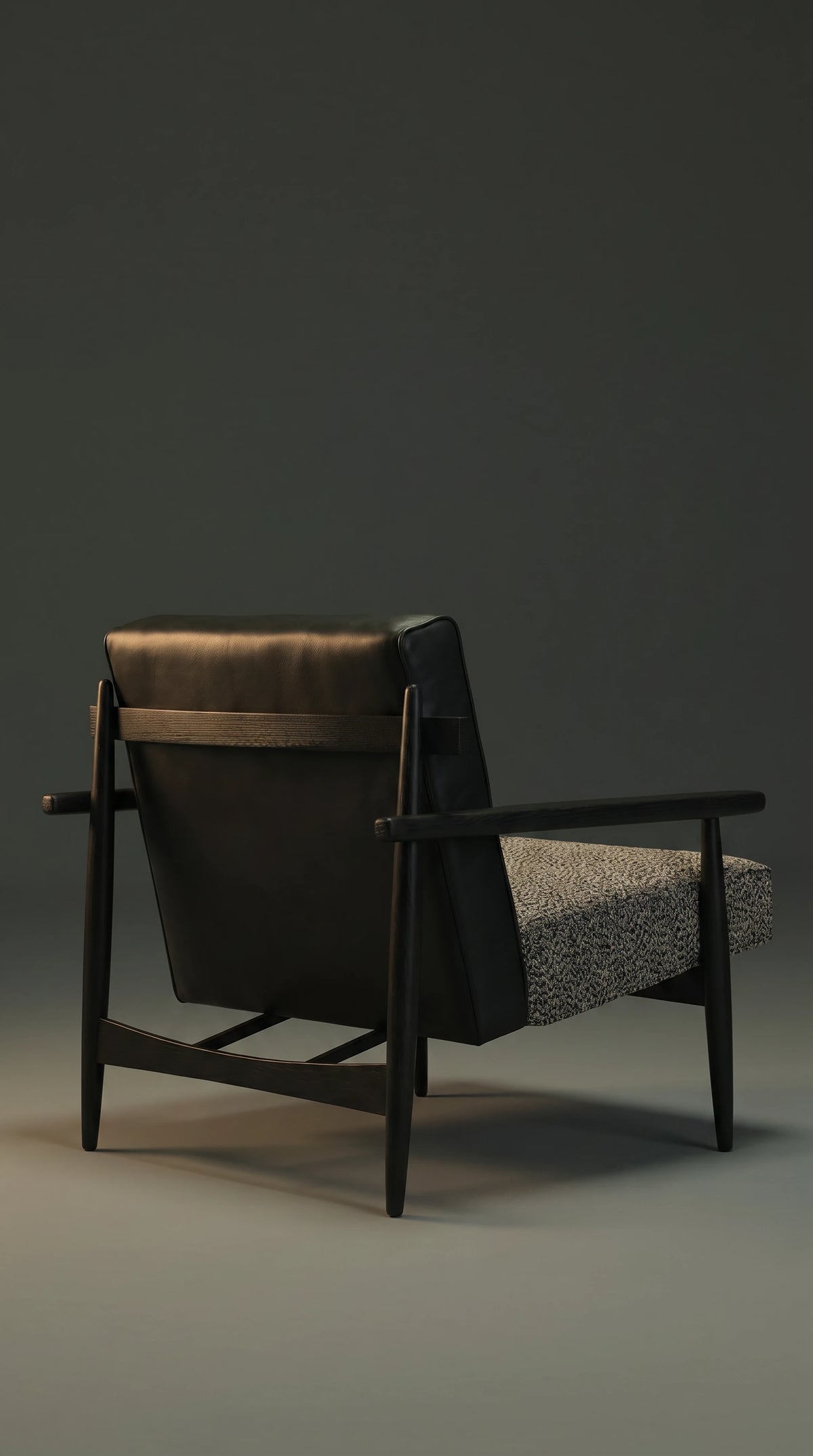 Rear view of the Retro Lounge armchair showing its black leather backrest, dark solid wood frame, circular back posts, and slim metal stretcher.