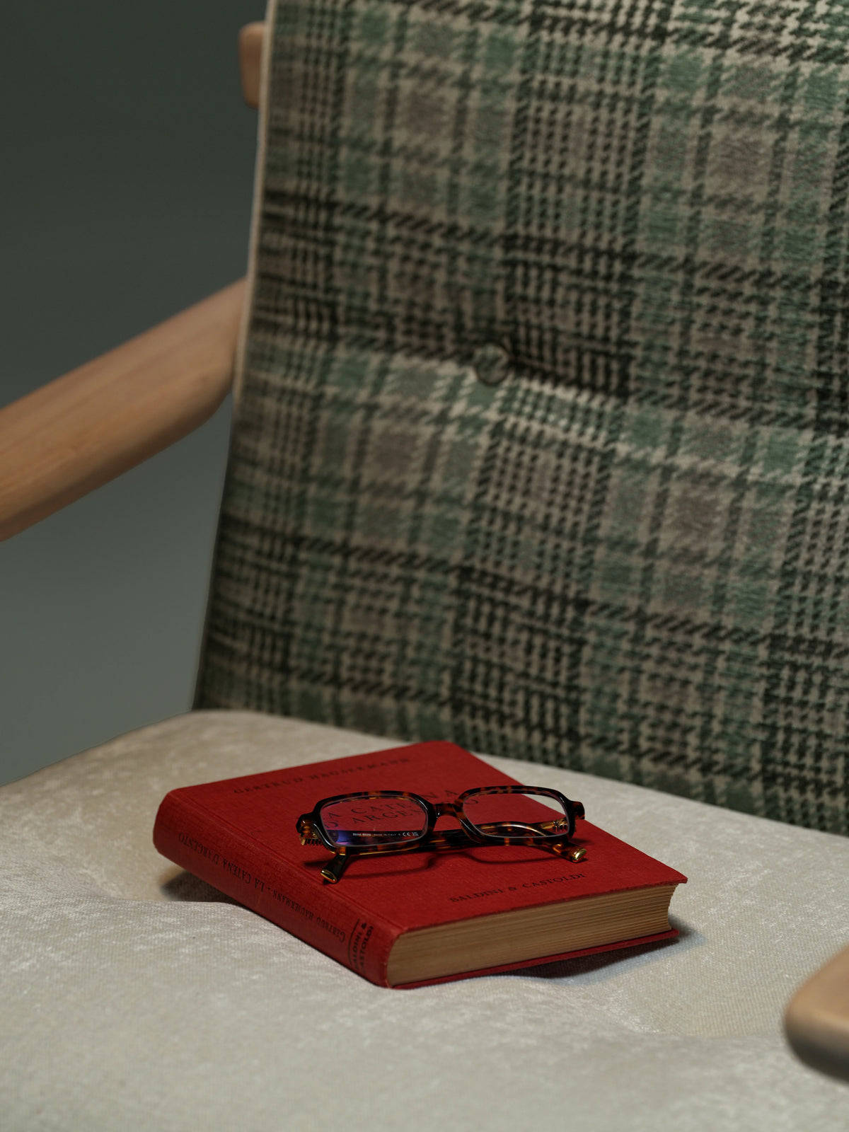 Close-up of the Retro Lounge armchair showing its plaid backrest, subtle capitonné button detailing, light seat cushion, and solid wood armrest.