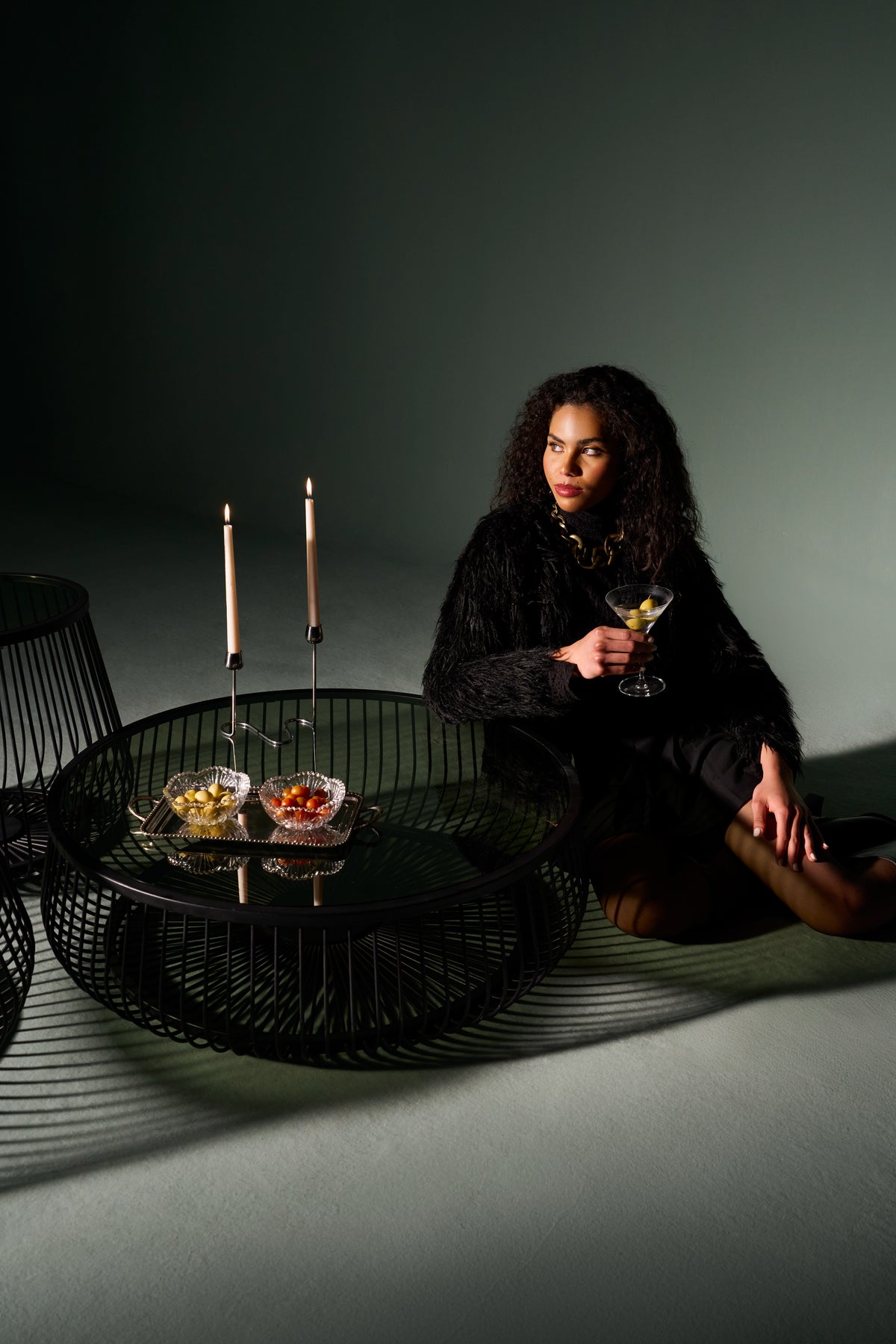 Model beside a set of Ring tables with round metal bases and glass tops, styled in a modern interior setting.