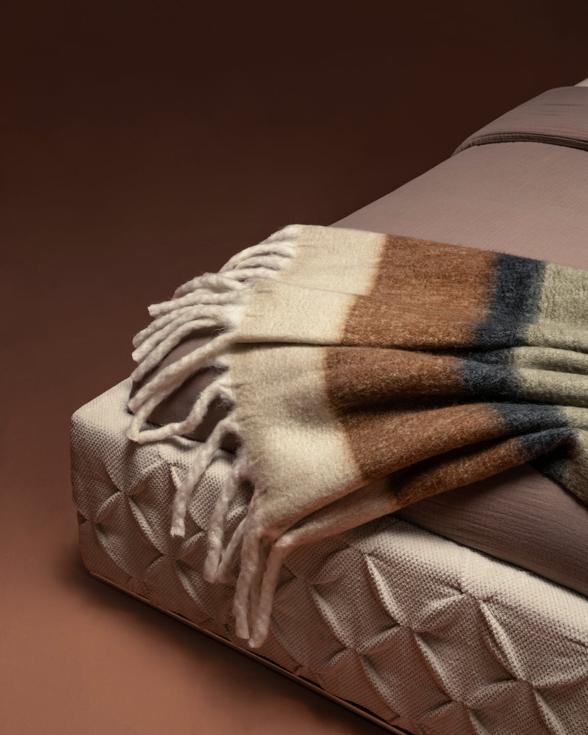 Close-up of Ro-Blocks bed corner showing hand-finished pinch pleating in cream fabric upholstery.