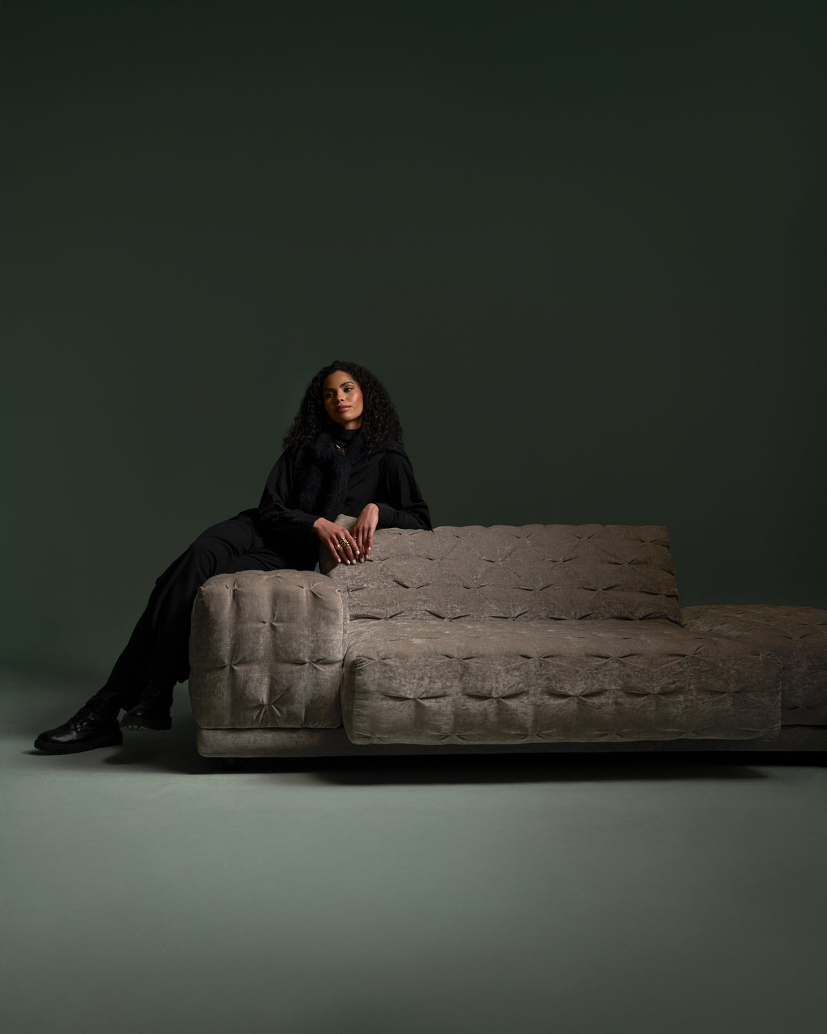 Model seated on the Ro-Blocks sofa in textured light brown fabric with modular block form and hand-pleated stitch upholstery detail.