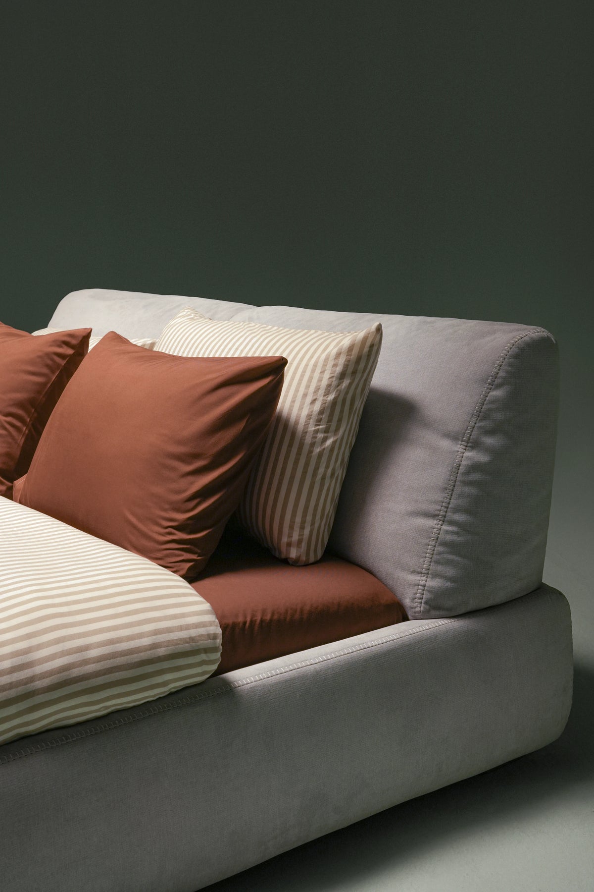Close view of the Snug bed’s grey upholstered adjustable backrest, recessed mattress and overcast stitching along the frame.